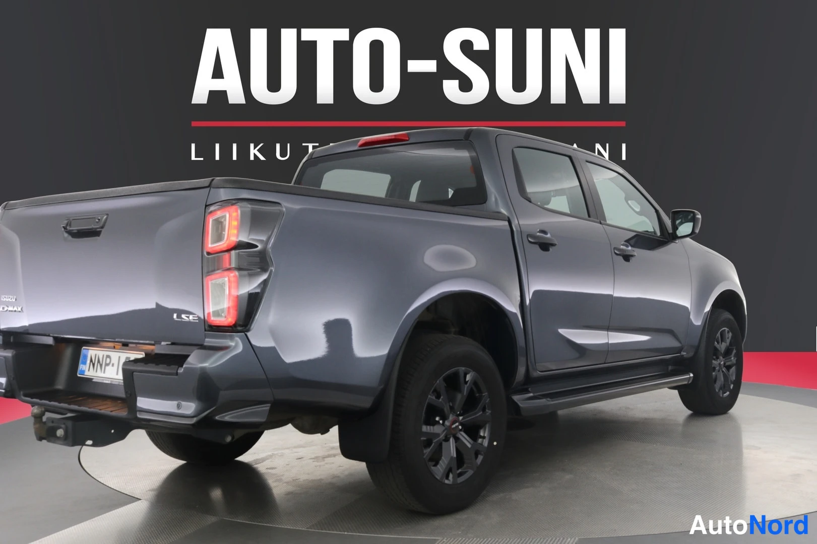 Takaviisto: Isuzu D-Max takaapäin ja sivulta kuvattuna, tummanharmaa lava ja vaalea rekisterikilpi.