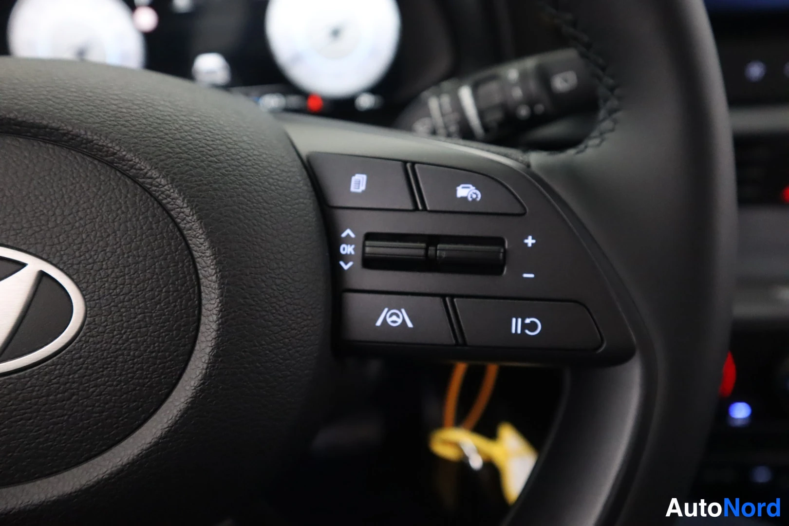 Yksityiskohta: Detailed view of the right side of the steering wheel showing Hyundai logo and buttons for menu selection (OK), cruise control icons (set/limit speeds), +/- vol