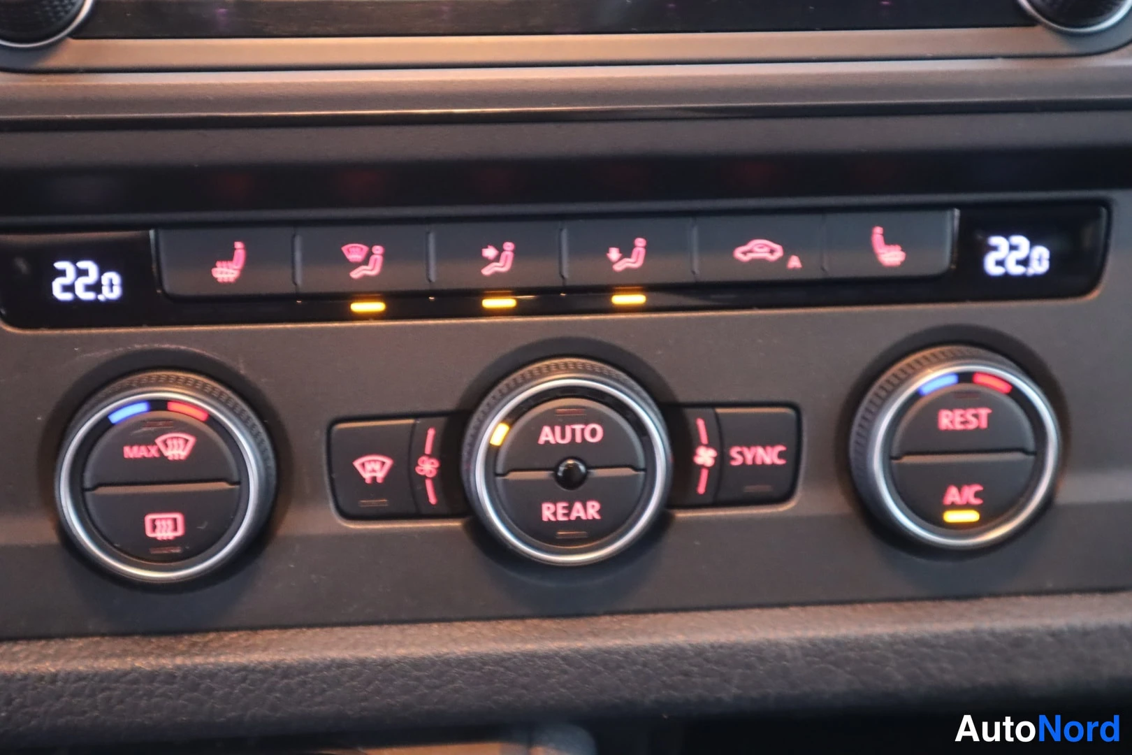 Yksityiskohta: Automaattisen ilmastoinnin säädinpaneeli, jossa kaksi 22,0 asteen näyttöä, AUTO-, REAR- ja SYNC-napit sekä REST/A/C-säädin.