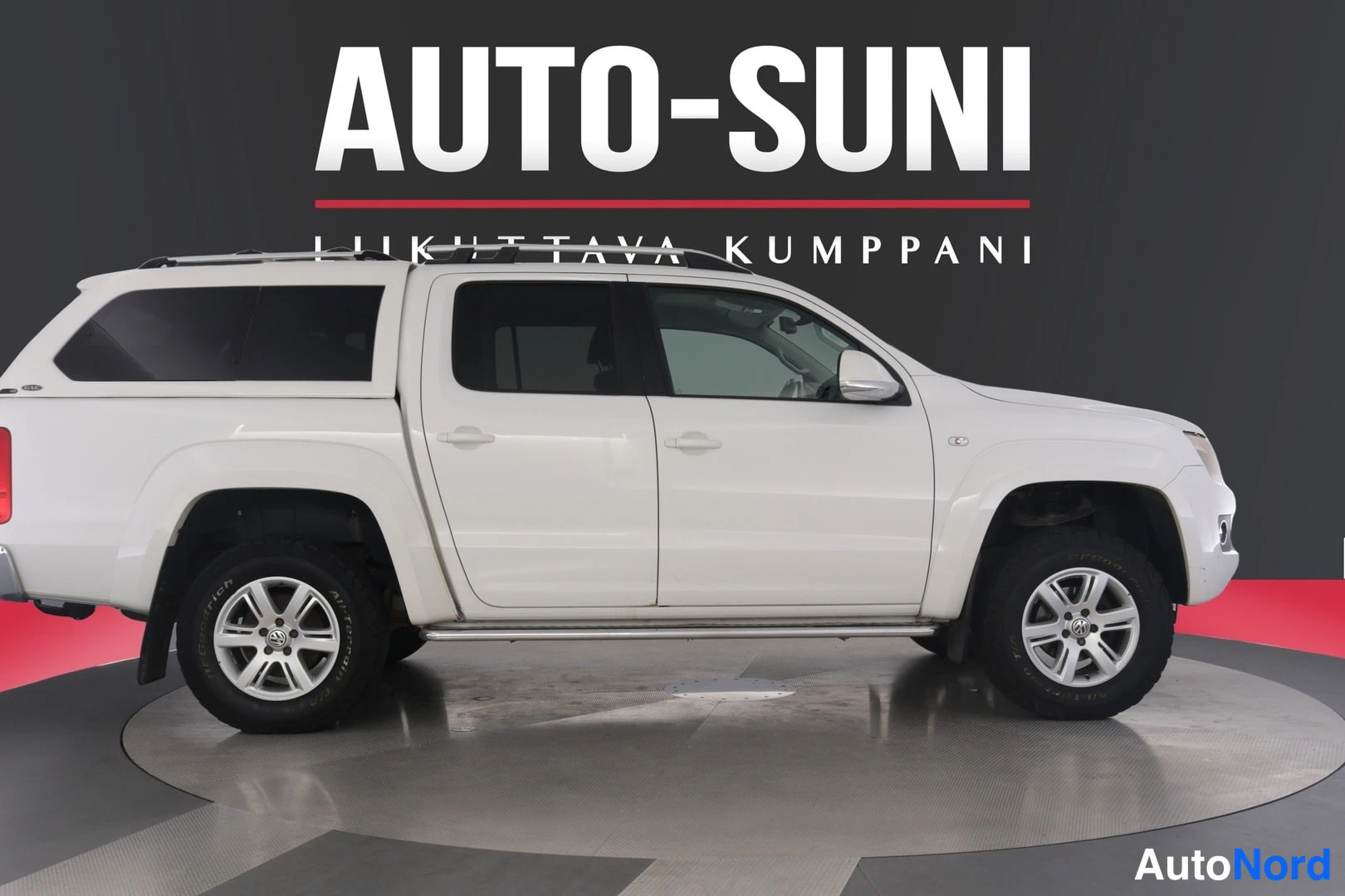 Sivulta: Valkoinen Volkswagen Amarok-neliovinen pickup sivulta vasemmalta, valkoinen kovakuori lavalla.