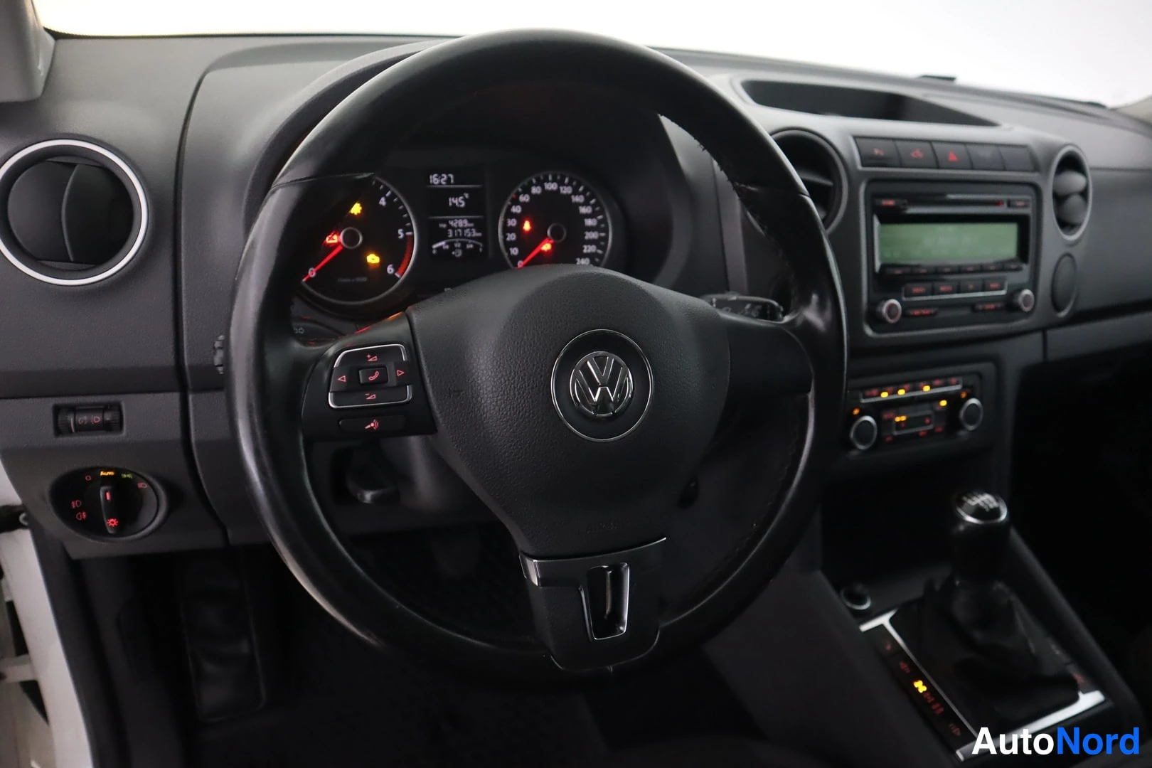 Muu: Kojelauta ja ohjauspyörä edestä kuvattuna: VW-tunnus rattiin, analogiset mittarit näkyvissä sekä radio- ja säätimien painikkeet keskirunkoryhmässä.