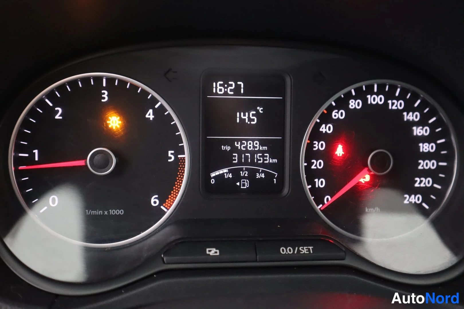 Muu: Kojelaudan mittarit lähikuvassa: näytössä aika 16:27, lämpötila 14,5 °C, matka 428,9 km ja kokonaislukema 317 153 km; varoitusvaloja syttyneenä.