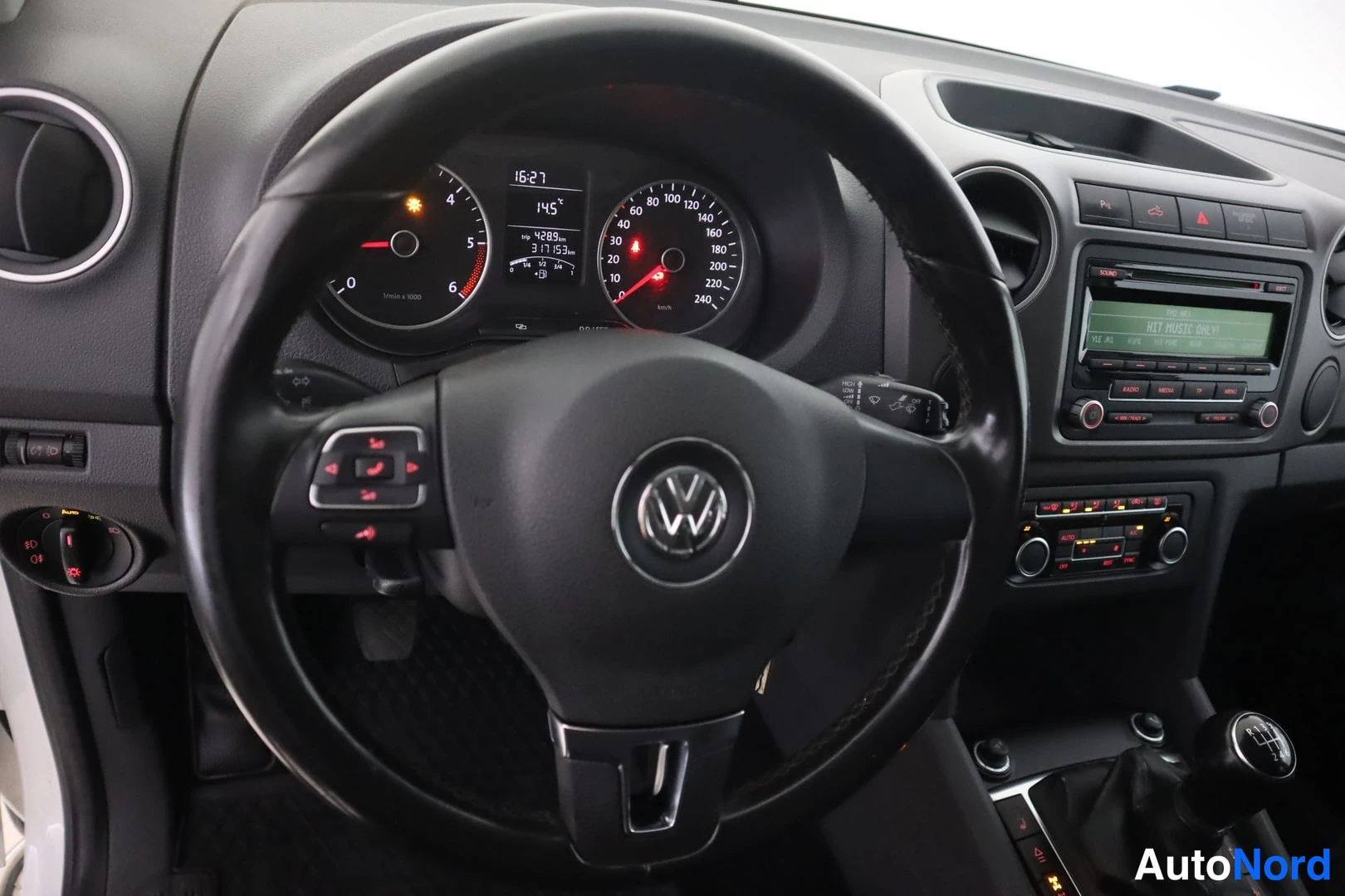 Yksityiskohta: Volkswagenin ohjaamo: VW-merkkinen multifunktionappainen ohjauspyörä, mittaristo ja keskikonsoli, jossa manuaalivaihteen tahdistin ja radioyksikkö. Matkamittari