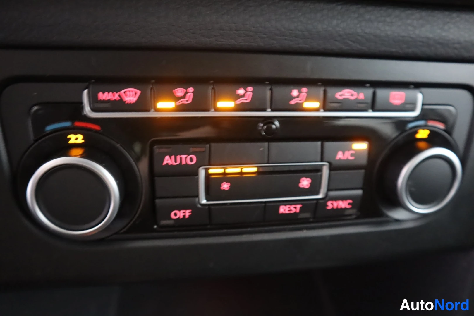Yksityiskohta: Automaattinen kaksivyöhykeilmastointi lähikuvassa: asetukset 22 ja 23 astetta sekä AUTO-, A/C-, SYNC-, OFF- ja REST-näppäimet. Muutamien lämmitysnäppäinten merk