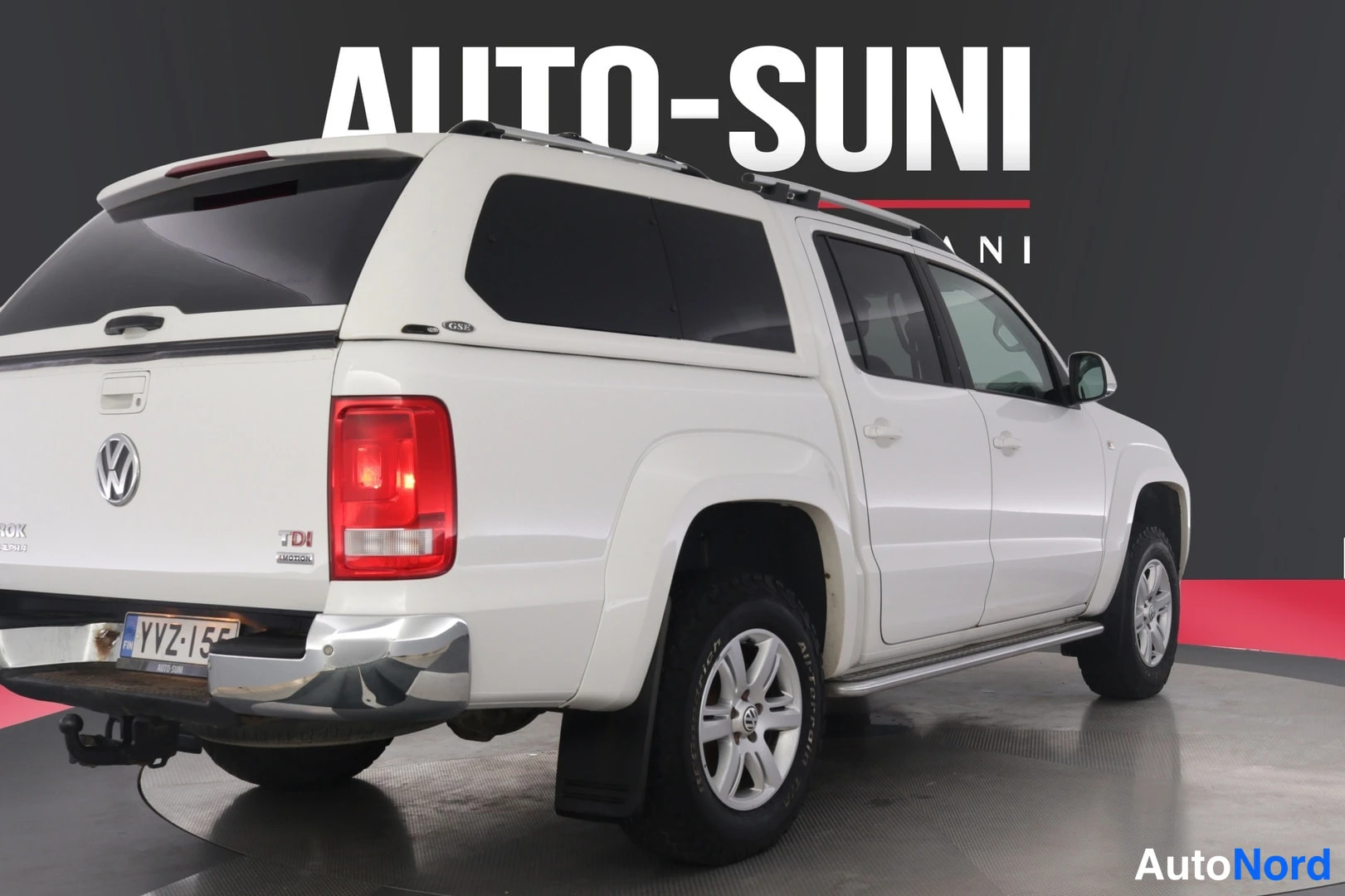 Takaviisto: Volkswagen Amarok pickup takakulmasta vasemmalta, punaiset takavalot, kromipuskuri ja valkoinen lavakori, rekisteri.