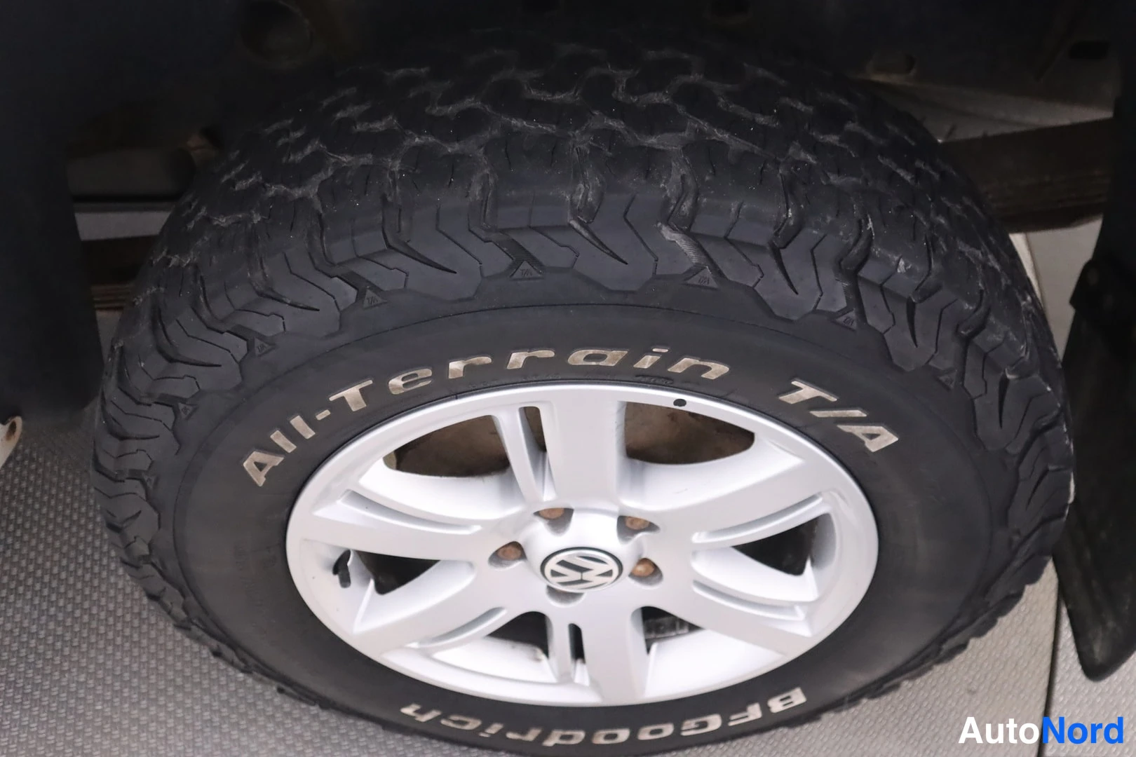 Yksityiskohta: Lähikuva BFGoodrich All-Terrain T/A -maastorenkaasta ja hopeavanteesta Volkswagen-merkillä.
