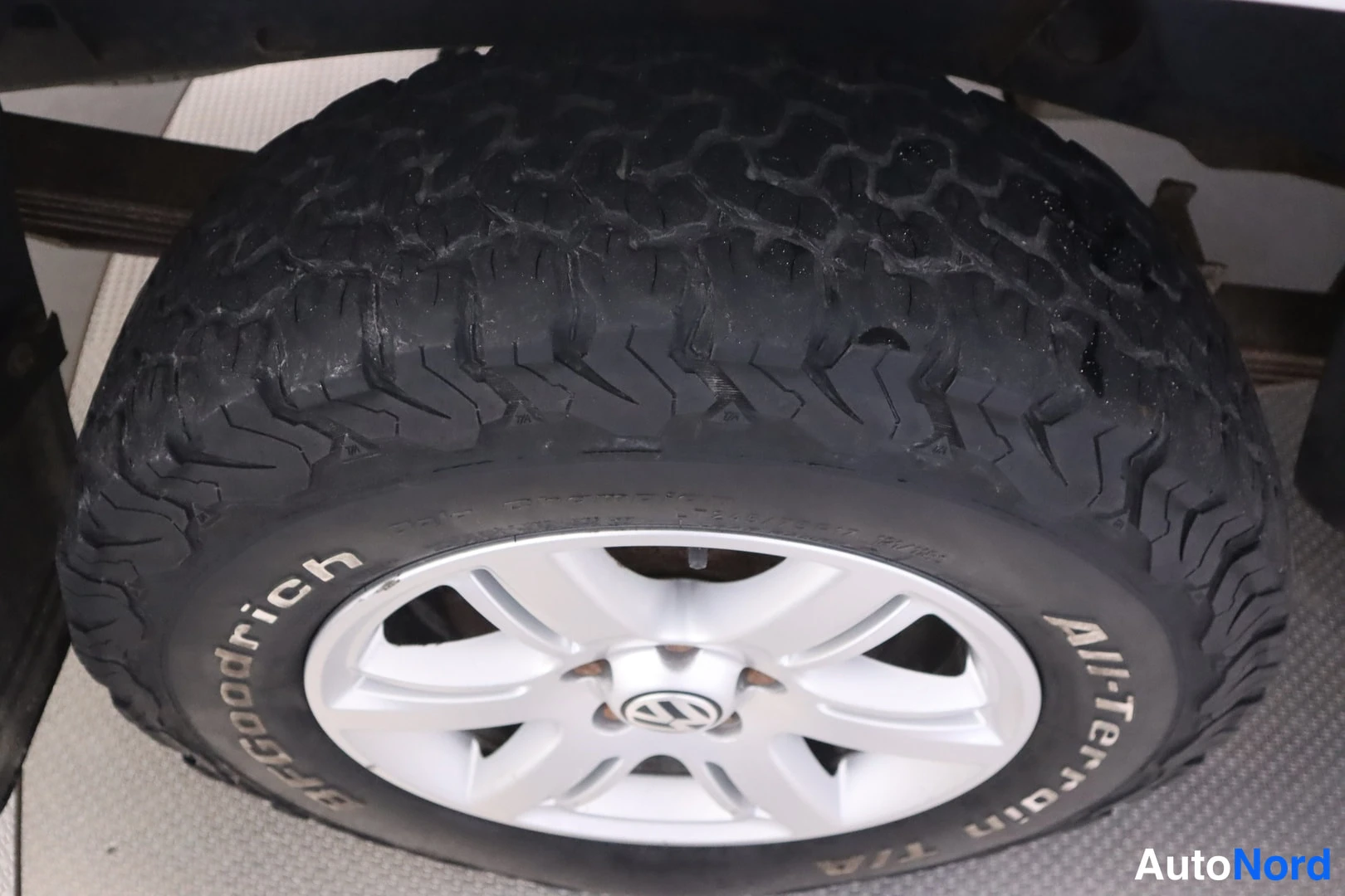 Yksityiskohta: Lähikuva kuluneesta BFGoodrich All-Terrain T/A -maastorenkaasta hopeavanteella.