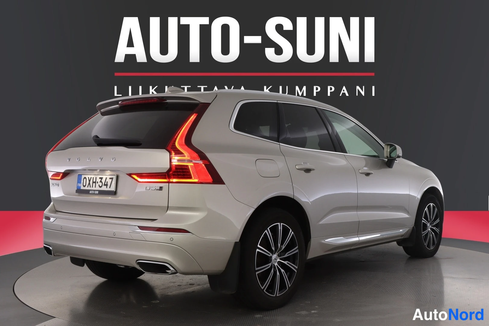 Takaviisto: Beige Volvo XC60:n takakulma vasemmalta, rekisterikilpi ja taustavalot valaistuna studiotaustaa vasten.