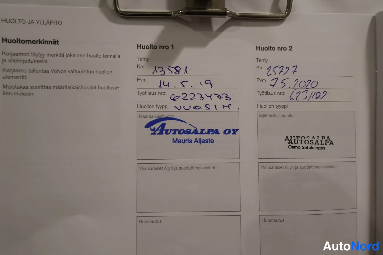 Yksityiskohta: Huoltokirjan sivu huolloista 1–2, käsin kirjoitetuilla kilometri- ja päivämäärätiedoilla.