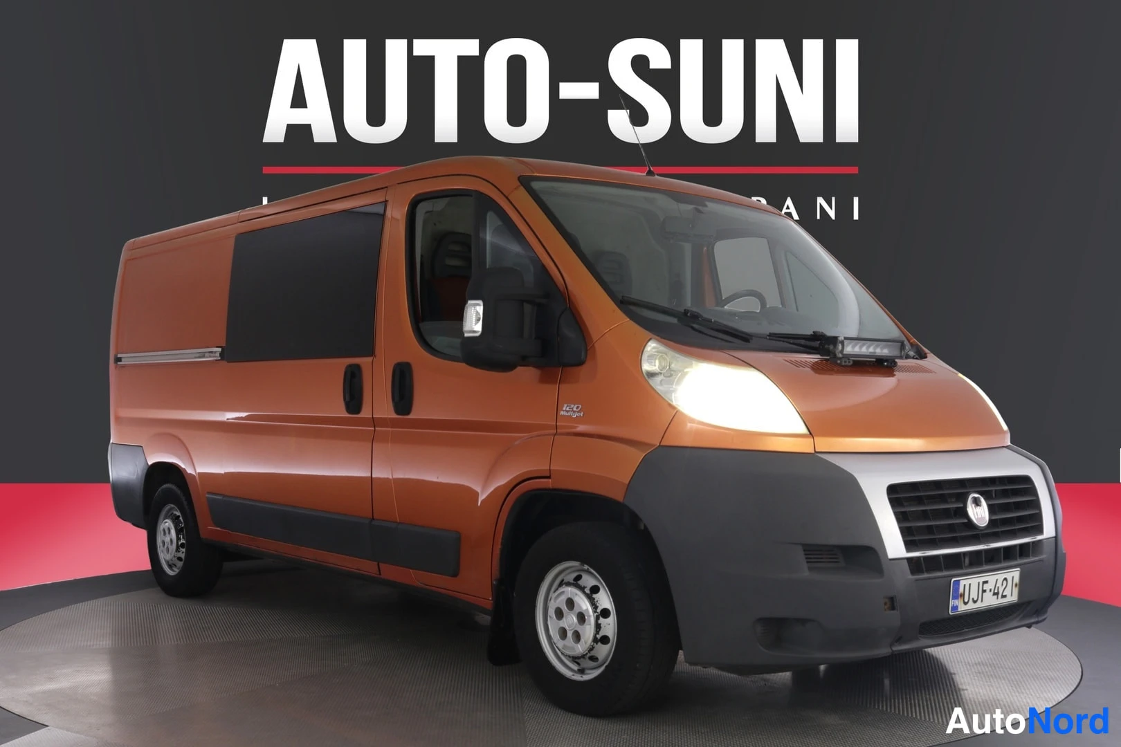 Etuviisto, nokka oikealle: Oranssi Fiat Ducato -pakettiauto etukulmasta oikealta kuvattuna Autotunin studiossa.