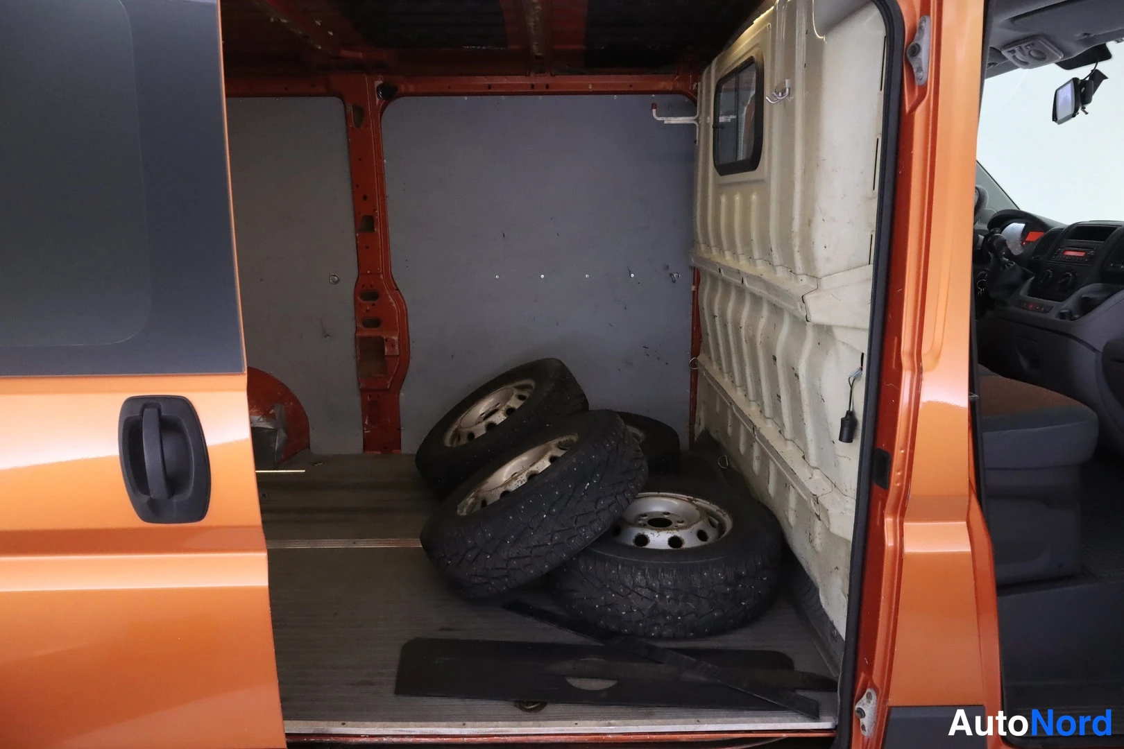 Takaa: Pakettiauton lastitila takamylkyssä: neljä talvirengasvannetta lattialla, seinät maalaamattomia ja valkoeristeisiä.