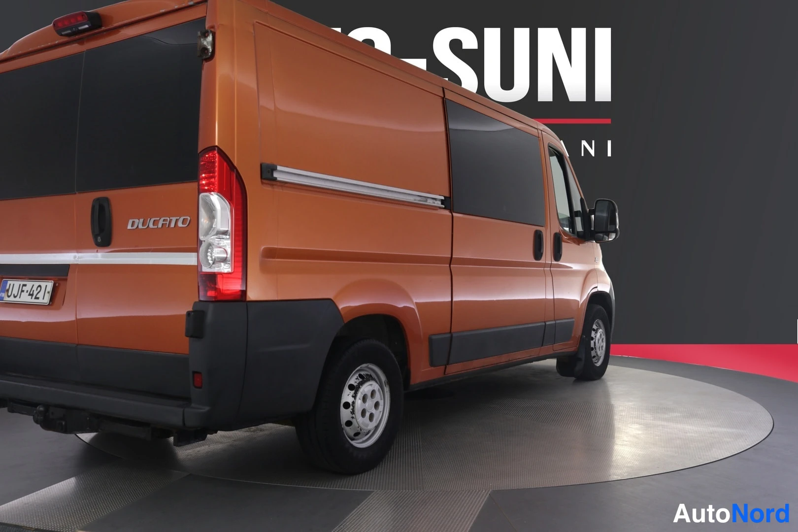 Takaviisto: Oranssi Fiat Ducato -pakettiauto takakulmasta vasemmalta kuvattuna, Ducato-teksti ja -kilpi näkyvissä.