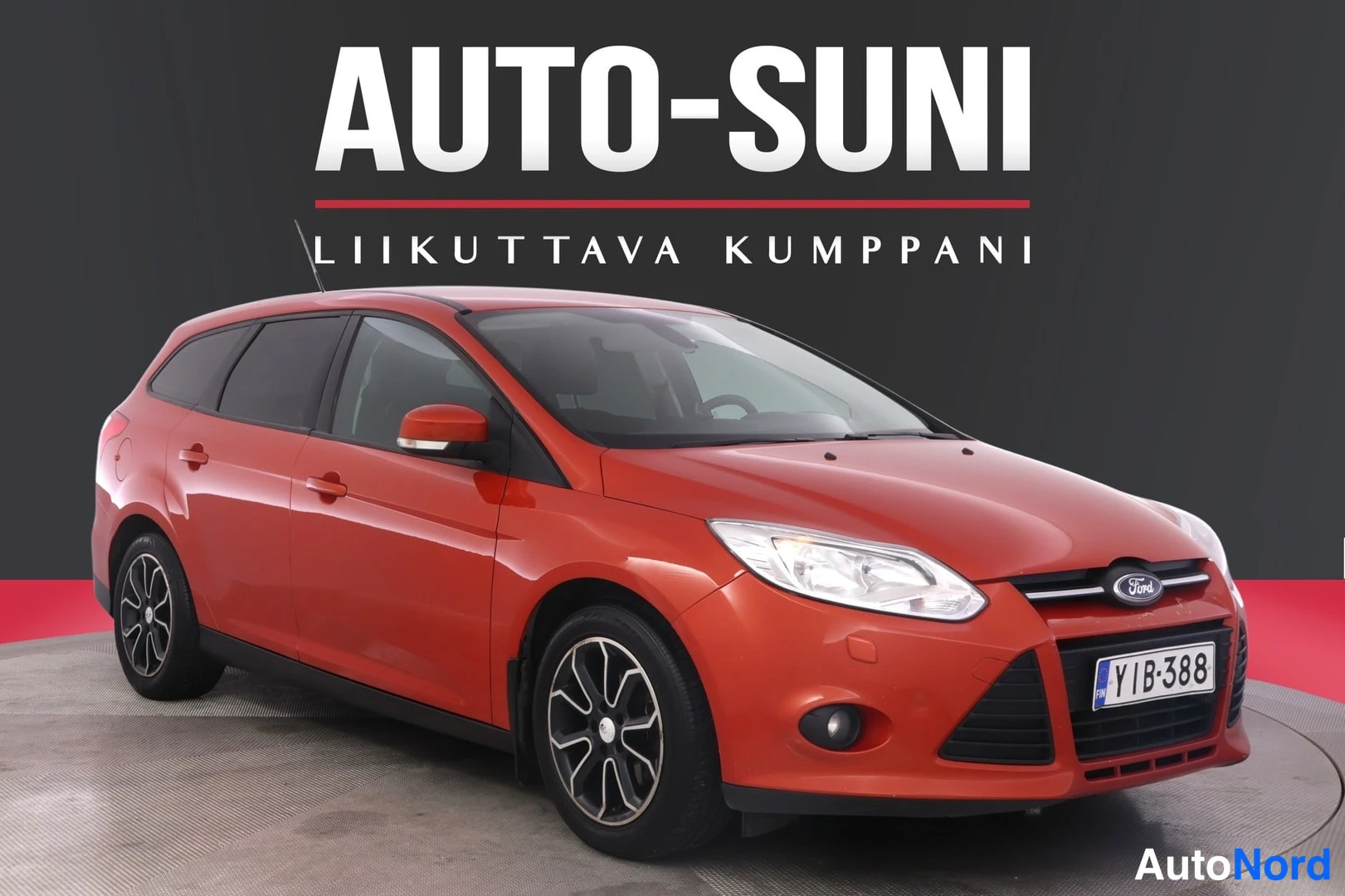 Etuviisto, nokka oikealle: Punainen farmariauto kolmasosakulmasta edestä oikealta, rekisteritunnuksella, mustalla taustalla AUTO-SUNI-logo.