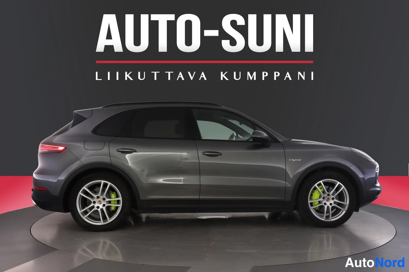 Sivulta: Porsche Cayenne 2020, tummanharmaa farmari-auto sivulta kuvattuna, vasen kylki näkyvissä, taustana AUTO-SUNI-mainos.