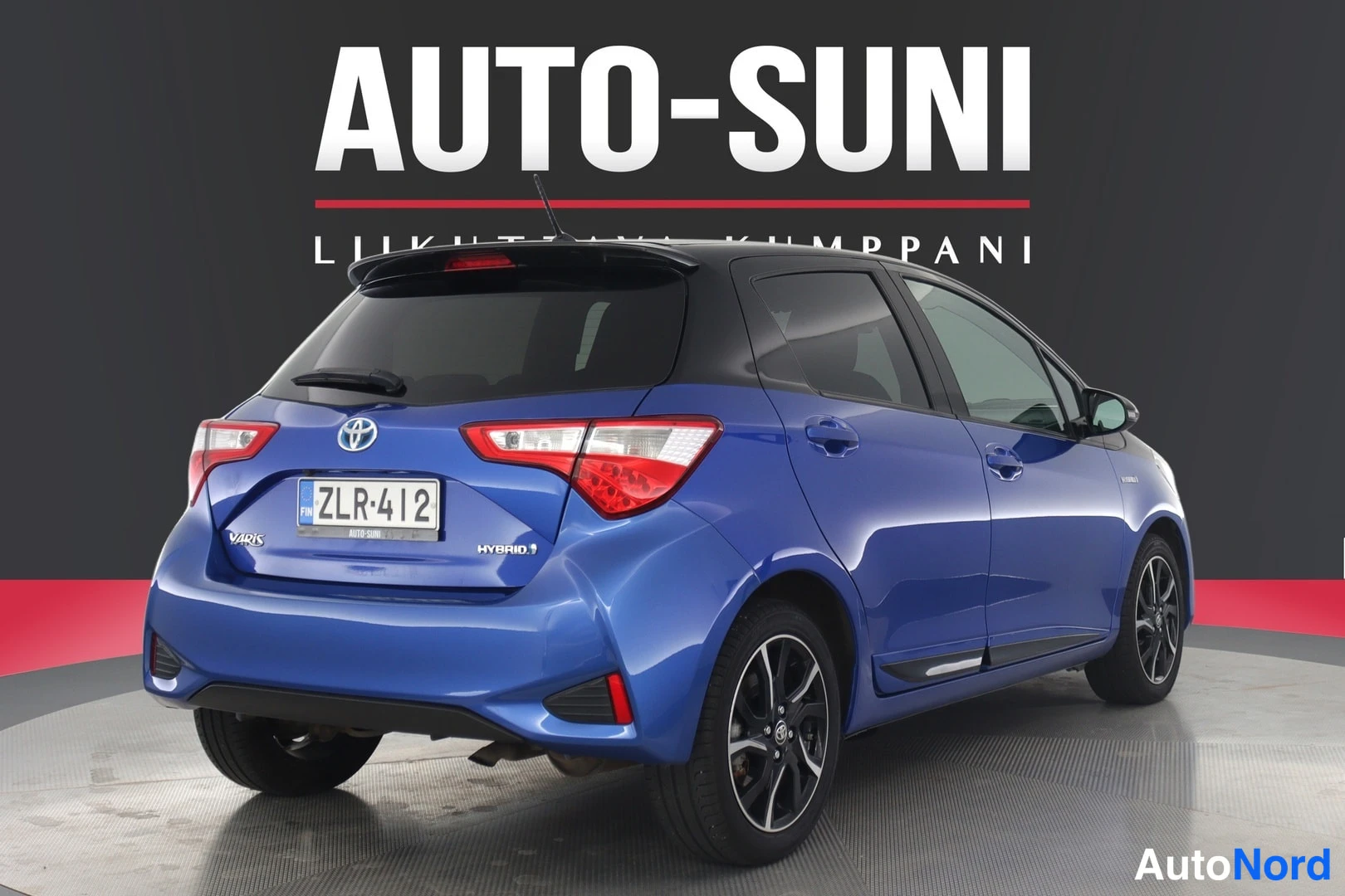 Takaviisto: Sininen Toyota Yaris -henkilöauto suoraan takaa kuvattuna studio-ympäristössä.
