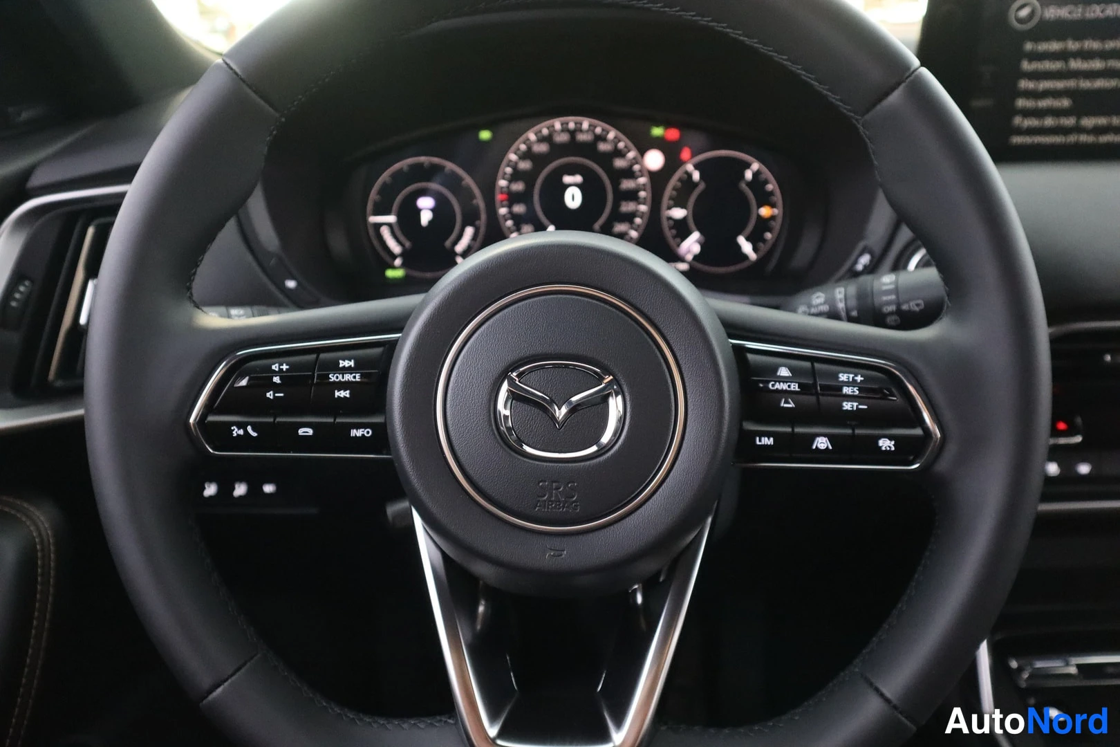Muu: Ohjauspyörä lähikuvassa: Mazda-logolla varustettu ilmatyynykoriste SRS AIRBAG-tekstillä, vasemmalla ääni- ja INFO-näppäimet, oikealla CANCEL, SET+, SET- ja LIM-