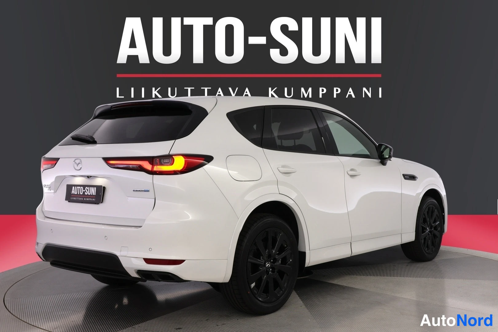 Takaviisto: Valkoinen Mazda CX-60 takaa sivusta kuvattuna, vasen kylki ja takavalot näkyvissä, tummat vanteet.