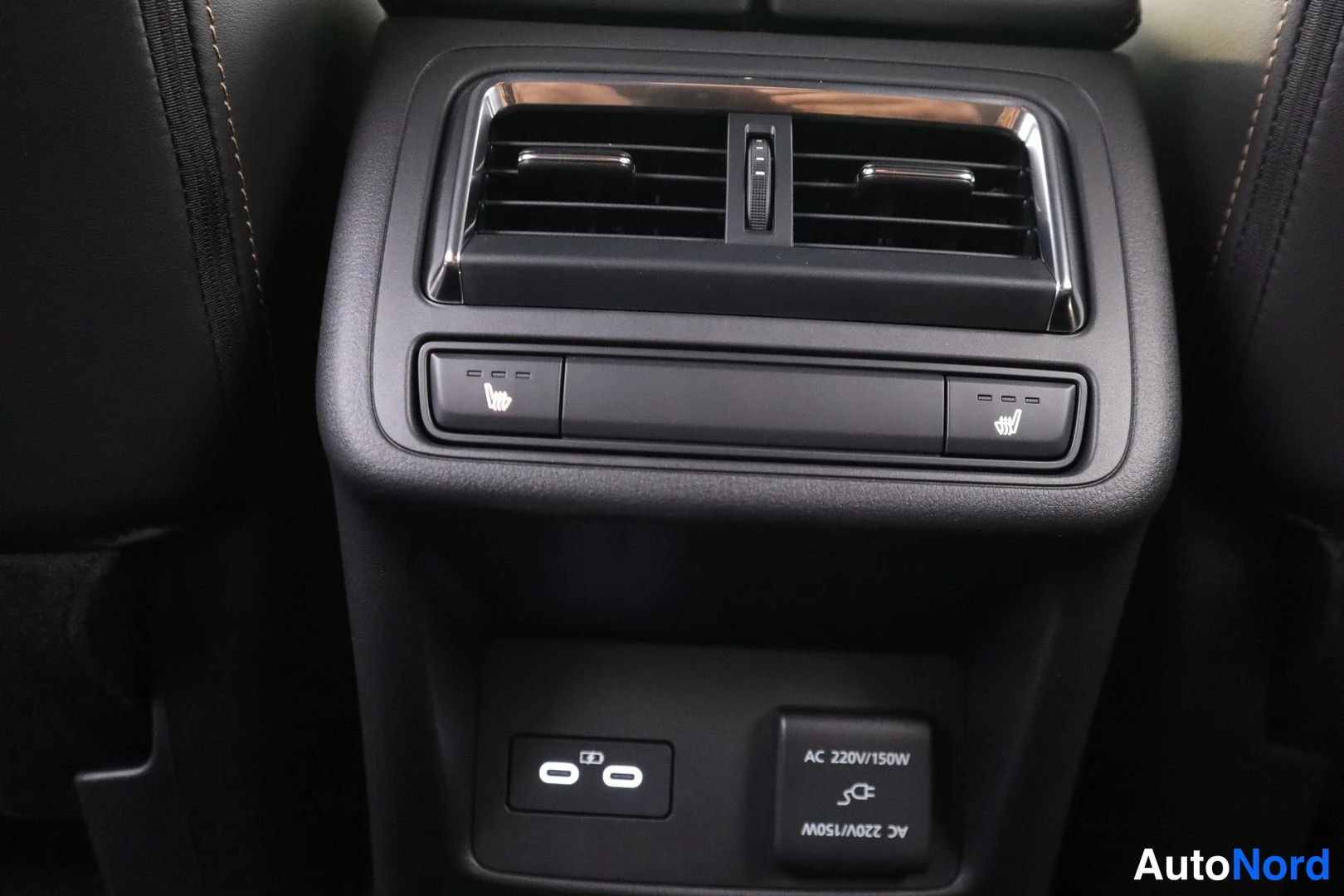 Muu: Takaistuimen keskikonsolin ilmastointiventtiilit ja heated seat -painikkeet; alapuolella 230 V pistorasia ja USB-portit.