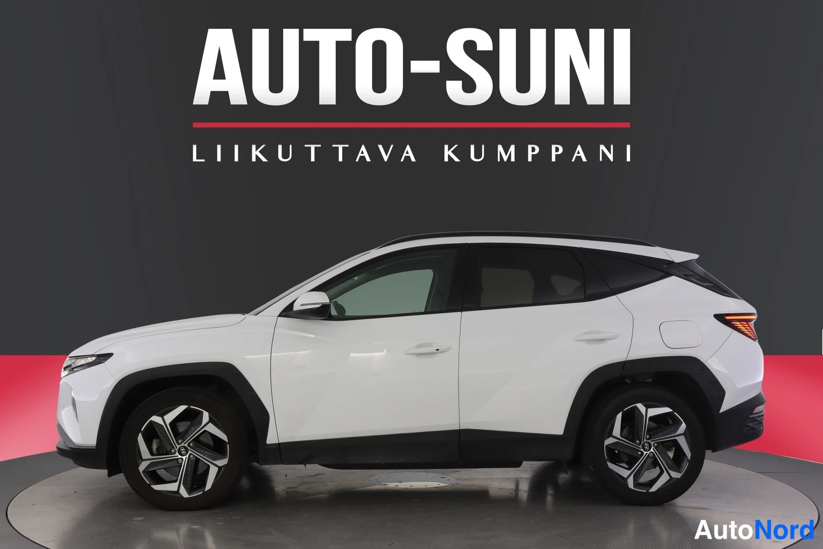 Sivulta: Valkoisen Hyundai Tucson -maasturin sivuprofiili studio-otoksessa, tummat pyörät ja katolle jatkuva tumma ikkunalinja.