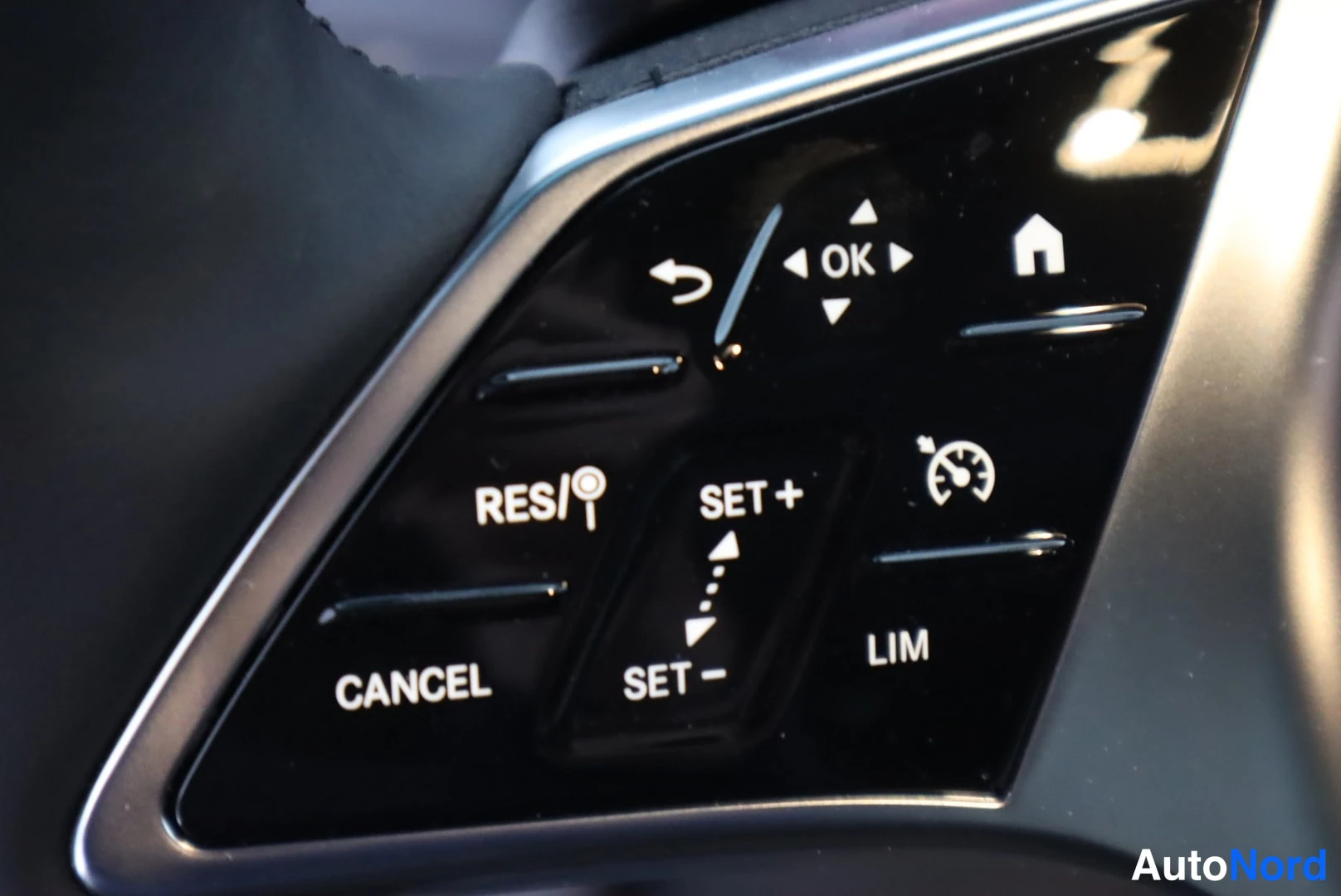 Yksityiskohta: Lähikuva Mercedes-Benzin ratissa olevasta kahvan oikean puolen näppäimistöstä, jossa näkyvät cruise control -toiminnot RES/, SET +, SET −, CANCEL ja LIM sekä nu