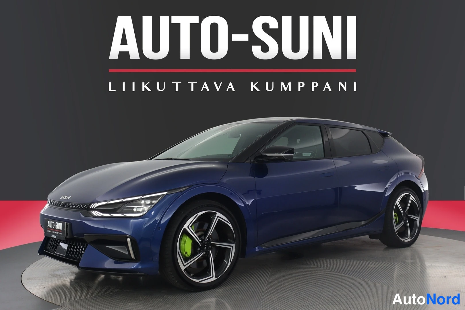 Etuviisto, nokka vasemmalle: Sininen Kia EV6 etukulmasta vasemmalle, parempi sivu näkyvissä, mustat vanteet neonvihreillä jarrusatuloilla.