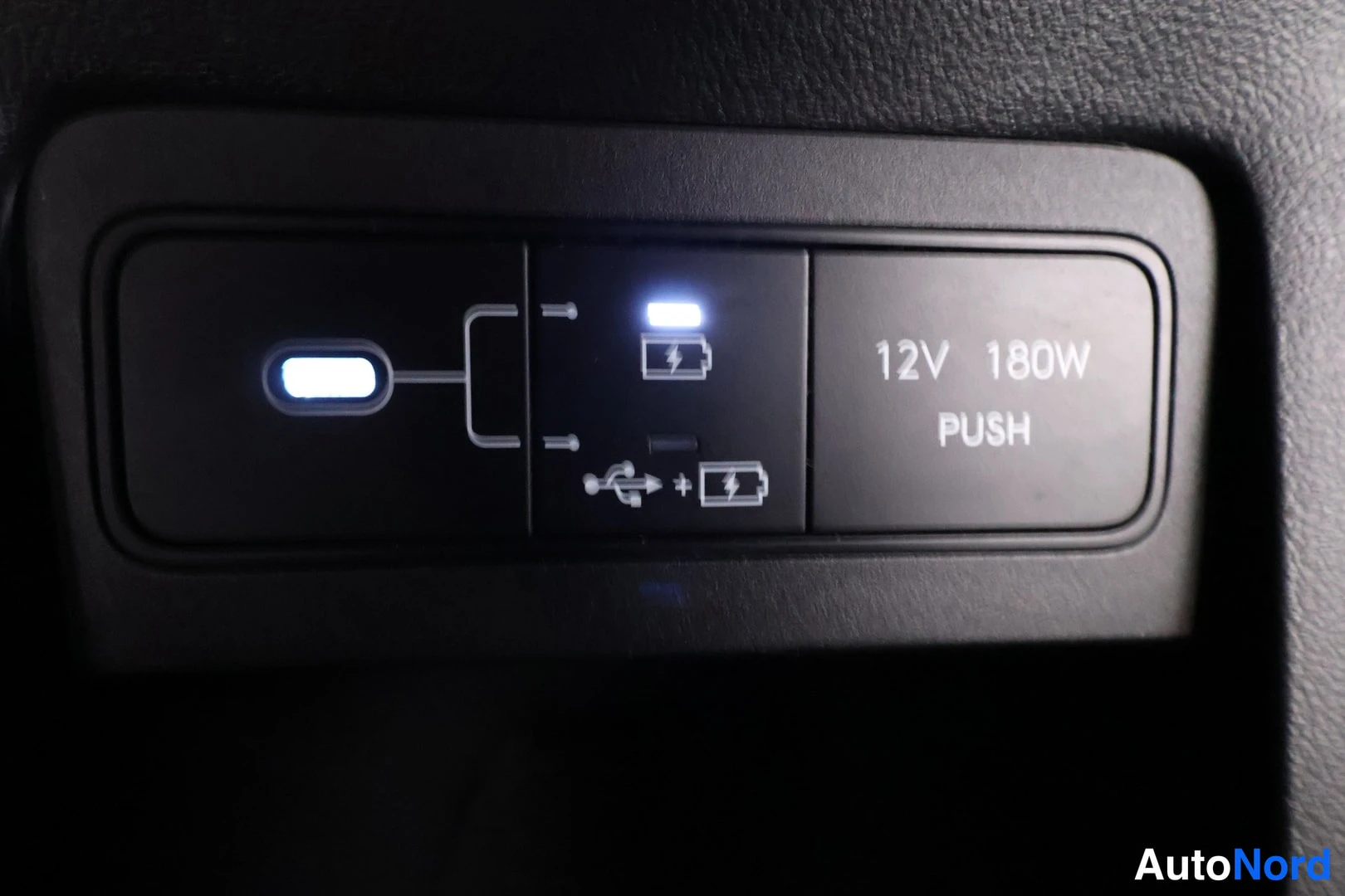 Yksityiskohta: Sisätilakuvan lähikuva: paneelissa USB-latausliitäntä, 12V 180W PUSH-pistorasian kansi ja USB-symbolit.
