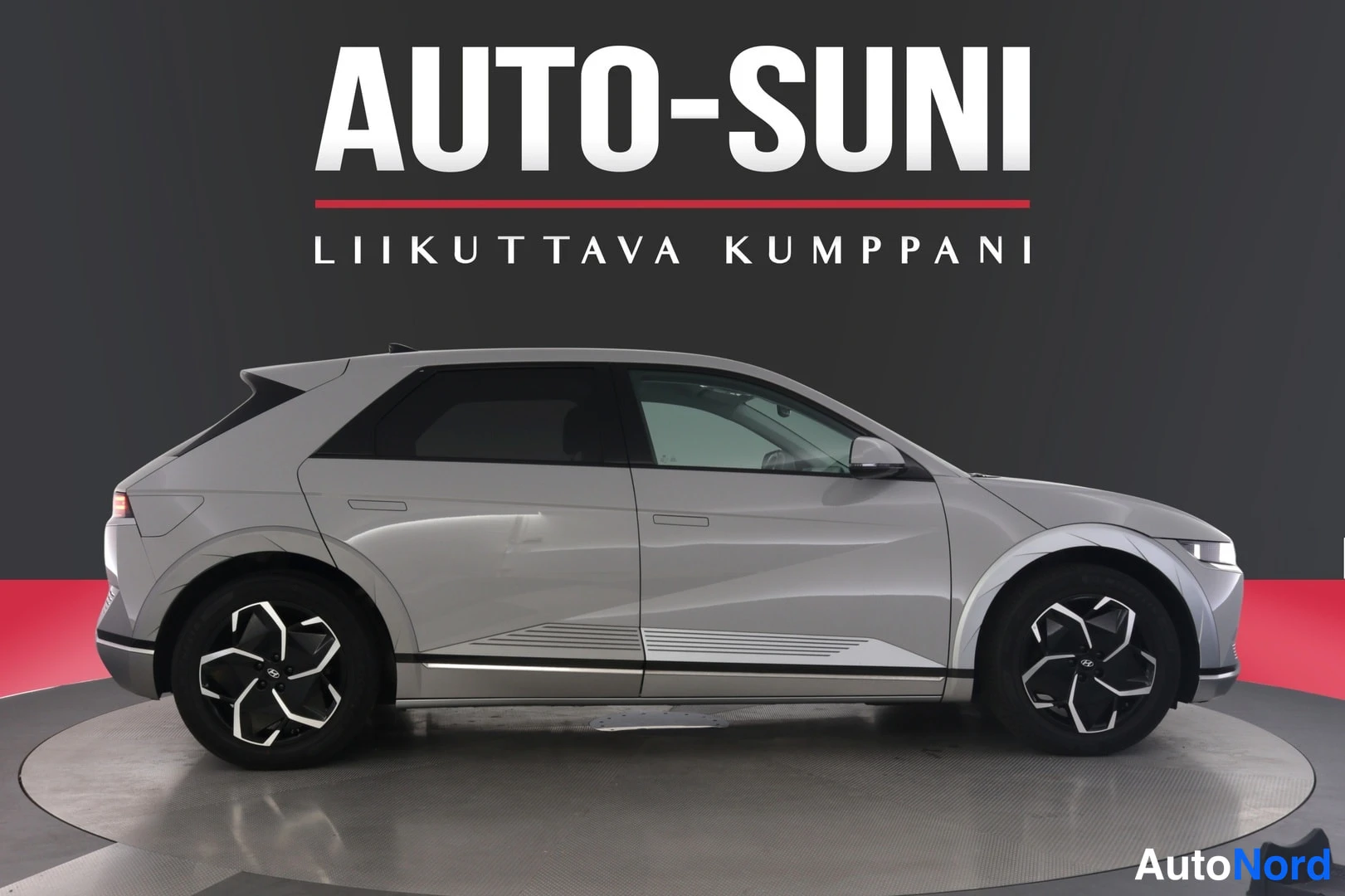 Sivulta: Autosuni-logo tummalla taustalla; hopeanharmaan Hyundai IONIQ 5:n sivuprofiili, kulmikkaat muodot ja kaksisakaraiset kevytmetallivanteet.