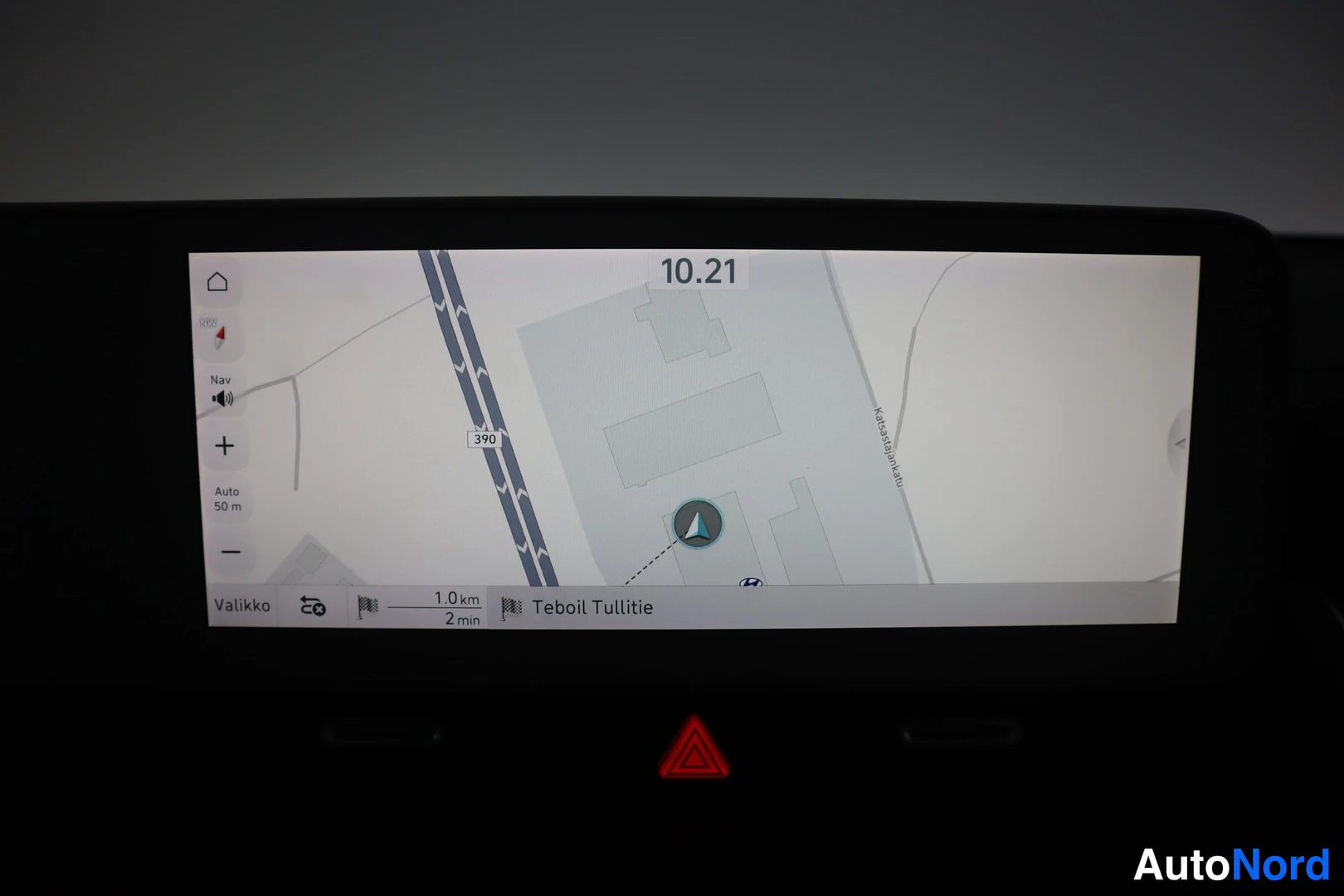 Yksityiskohta: Infotainment-näytön navigaatiokartta, jonka alareunassa lukee 1.0 km, 2 min ja Teboil Tullitie.