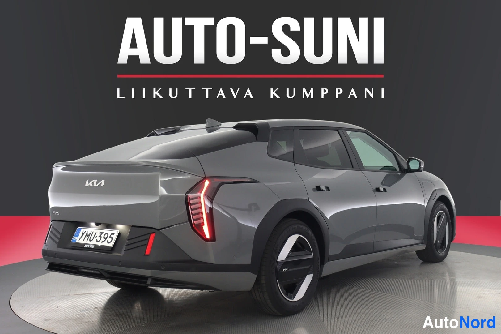 Takaviisto: Kia EV4, takaosa kolmesta neljäsosasta näkyvissä, harmaa koripaneeli, Kia-merkki ja rekisterikilpi YMÜ-395 takaluukussa
