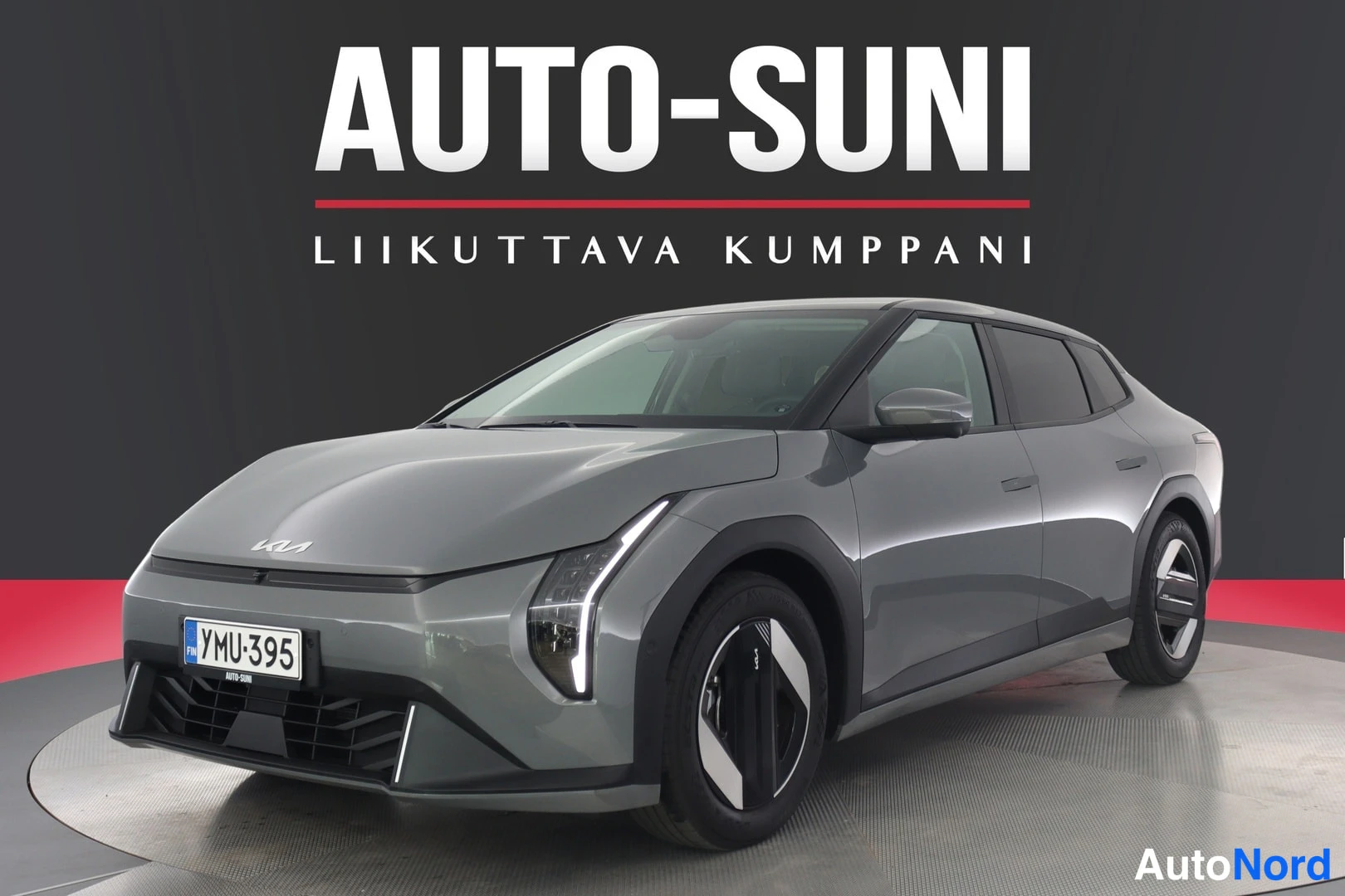 Etuviisto, nokka vasemmalle: Harmaan Kia EV4:n etukulmanäkymä rekisterikilpi näkyvissä, Auto-Suni-tausta.