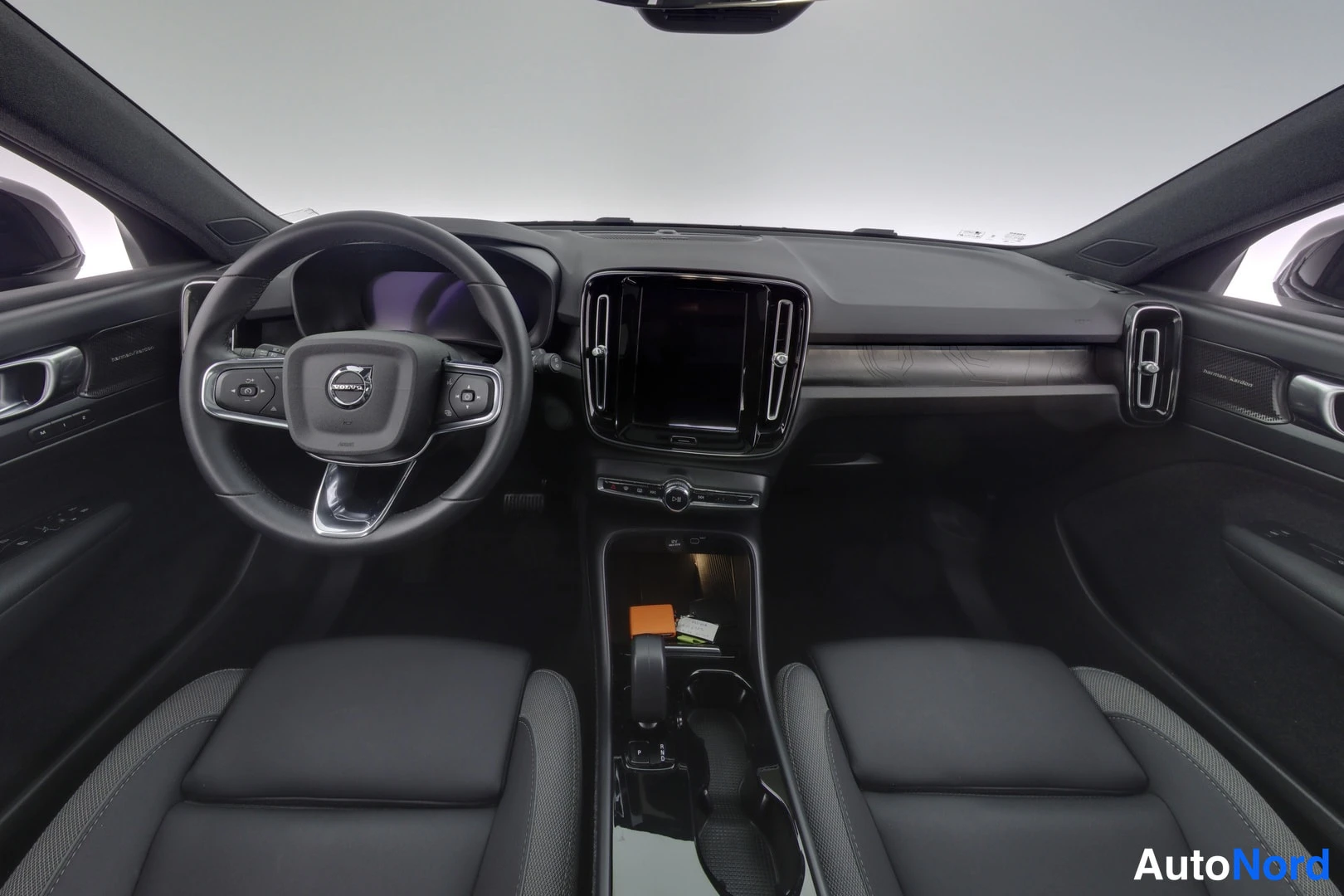 Edestä: Volvo XC40:n ohjaamo etupenkkien takaa, ohjauspyörä ja keskikonsolin näyttö.