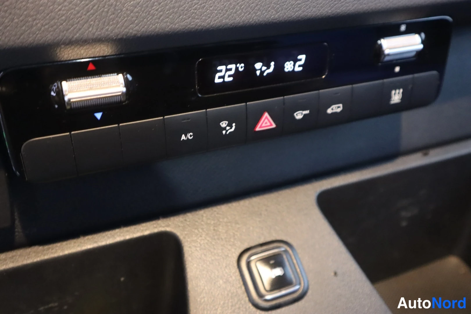 Yksityiskohta: Sisätilan lähikuva Mercedes-Benzin kojelaudan ilmastointipaneelista, näytössä 22 °C ja A/C-painike