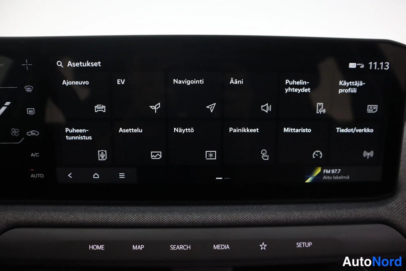 Yksityiskohta: Auton infotainment-näyttö Asetukset-valikossa, jossa ovat valinnat Ajoneuvo, EV, Navigointi, Ääni, Puhelin-yhteydet ja Käyttäjäprofiili.