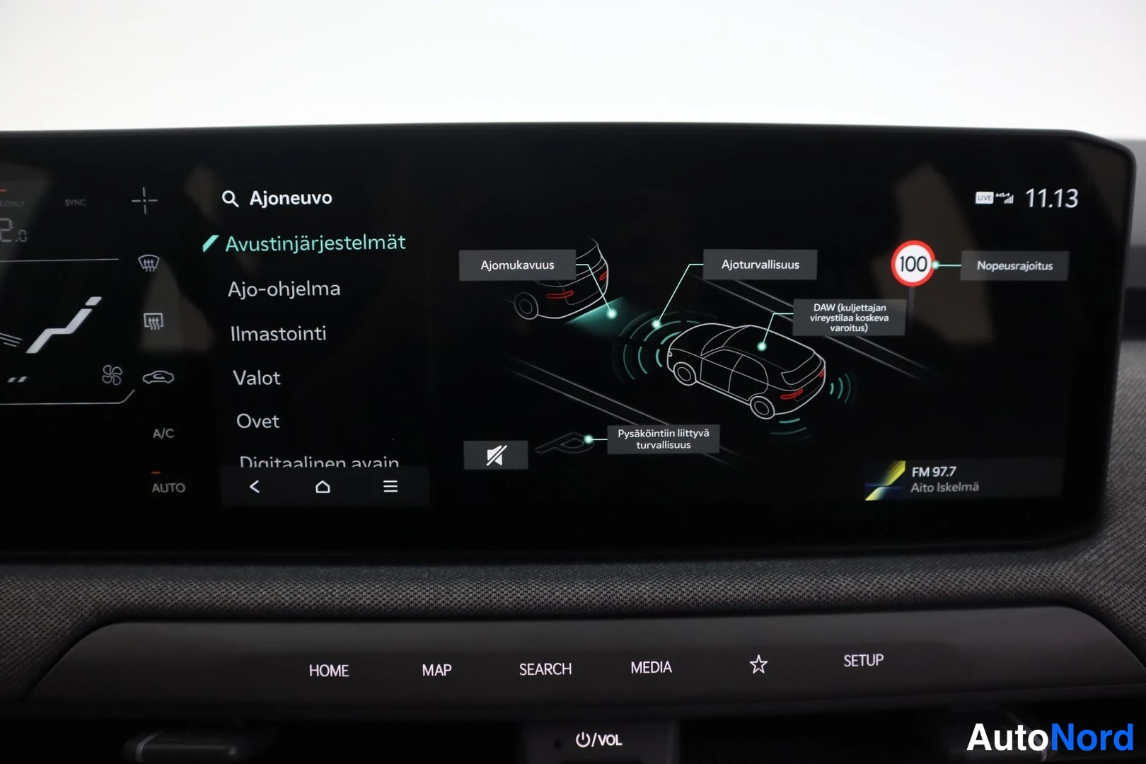 Yksityiskohta: Infotainment-näytön Ajoneuvo-valikko, Avustinjärjestelmät-osio avattuna, vasemmalla listat muita valikkoja kuten Ajo-ohjelma ja Ilmastointi.