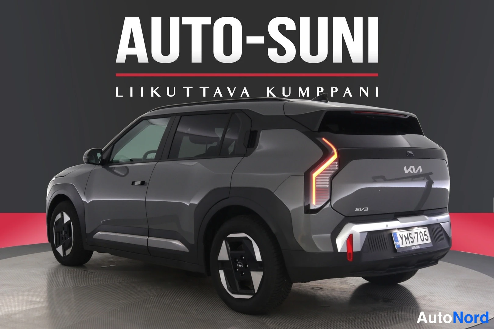 Takaviisto: Auton takakulma valokuvausstudiossa, harmaanruskean Kia EV3:n takavalot, EV3-merkintä ja rekisteritunnus.