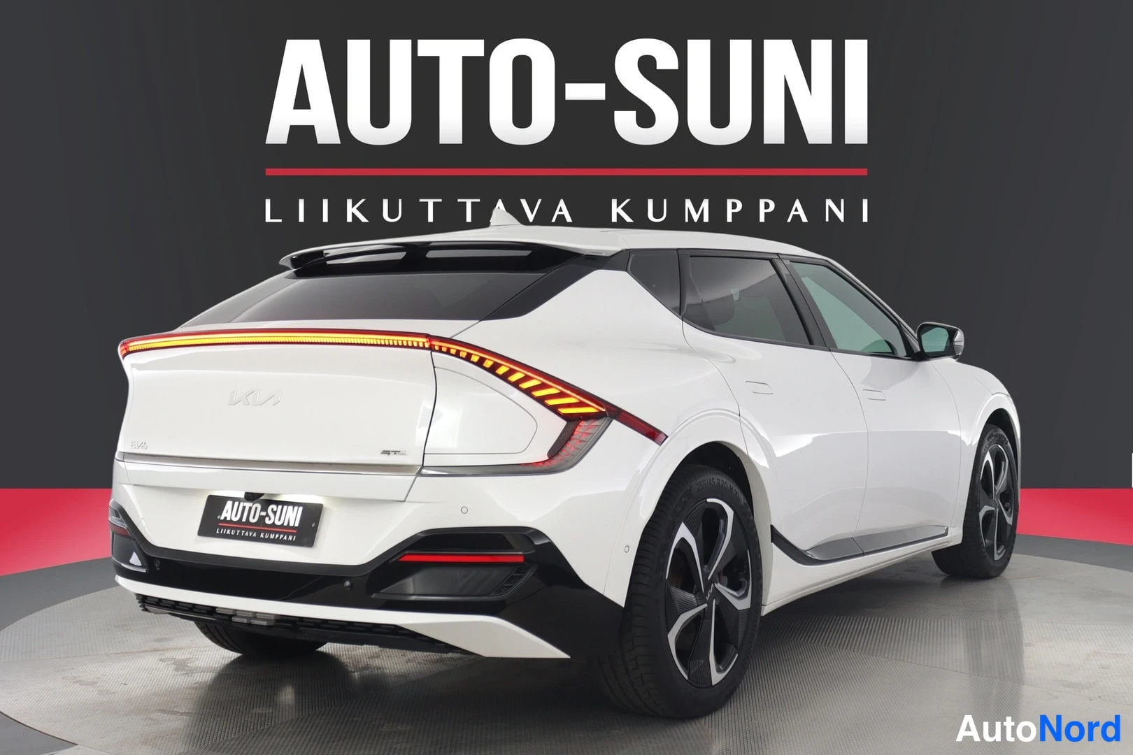 Takaa: Valkoinen Kia EV6 suoraan takaa, virittynyt takavalo, Kia-kyltti kannessa ja AUTO-SUNI-kyltti rekisterikilven paikalla.