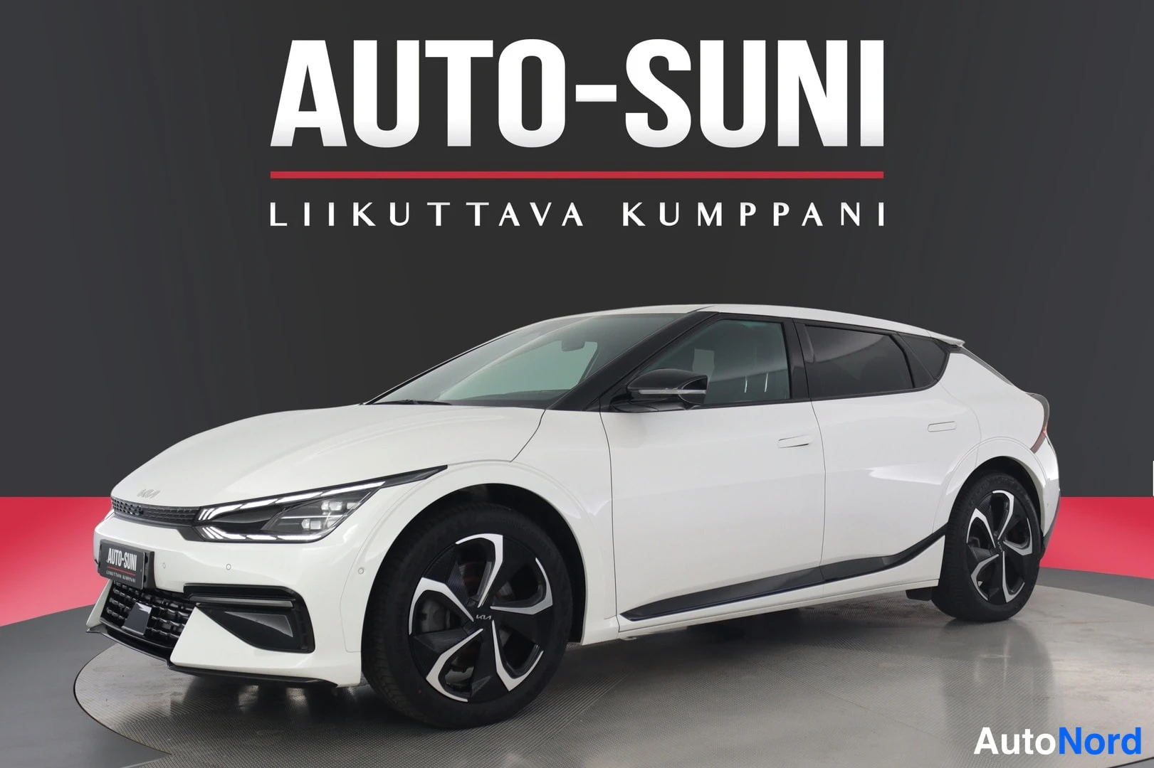 Etuviisto, nokka vasemmalle: Valkoinen Kia EV6 kuvattu etuviistosta vasemmalta, keulavalot ja mustat vanteet näkyvät.