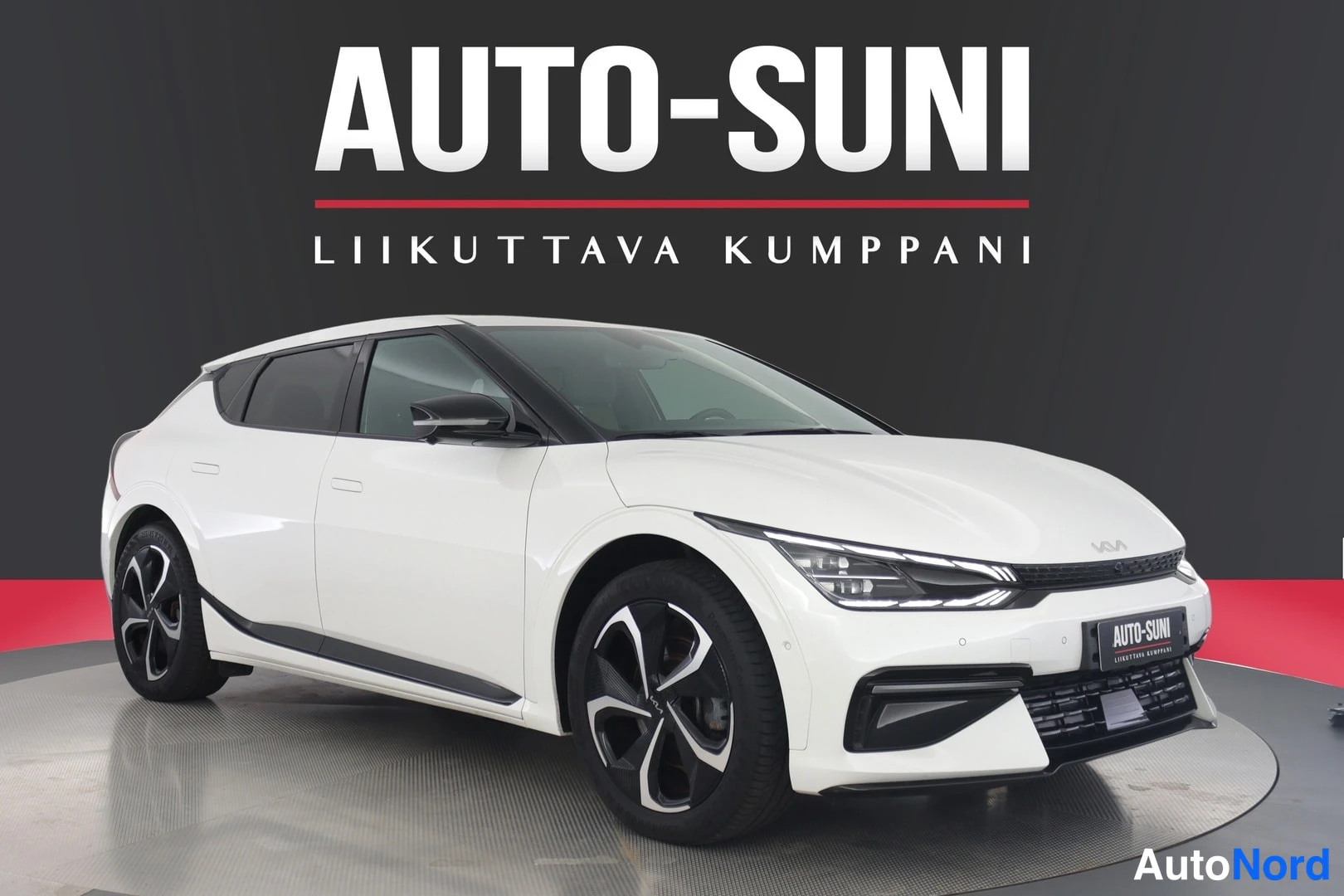 Etuviisto, nokka oikealle: Valkoinen Kia EV6 etukulmasta oikealta, Kia-kyltti etusäleikössä, mustat kevytmetallivanteet ja musta koroketikorko.