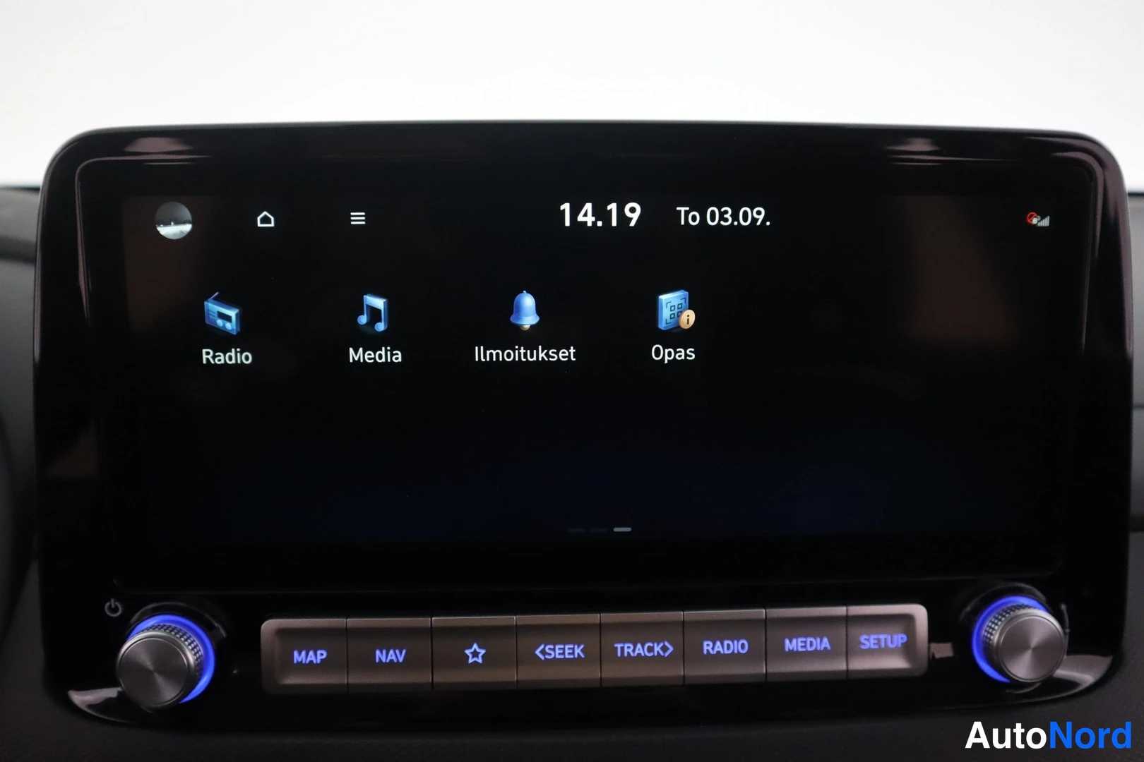 Muu: Auton infotainment-näytön päävalikko kuvakkeilla Radio, Media, Ilmoitukset ja Opas; näytön alla fyysiset painikkeet ja kaksi säätönappia.