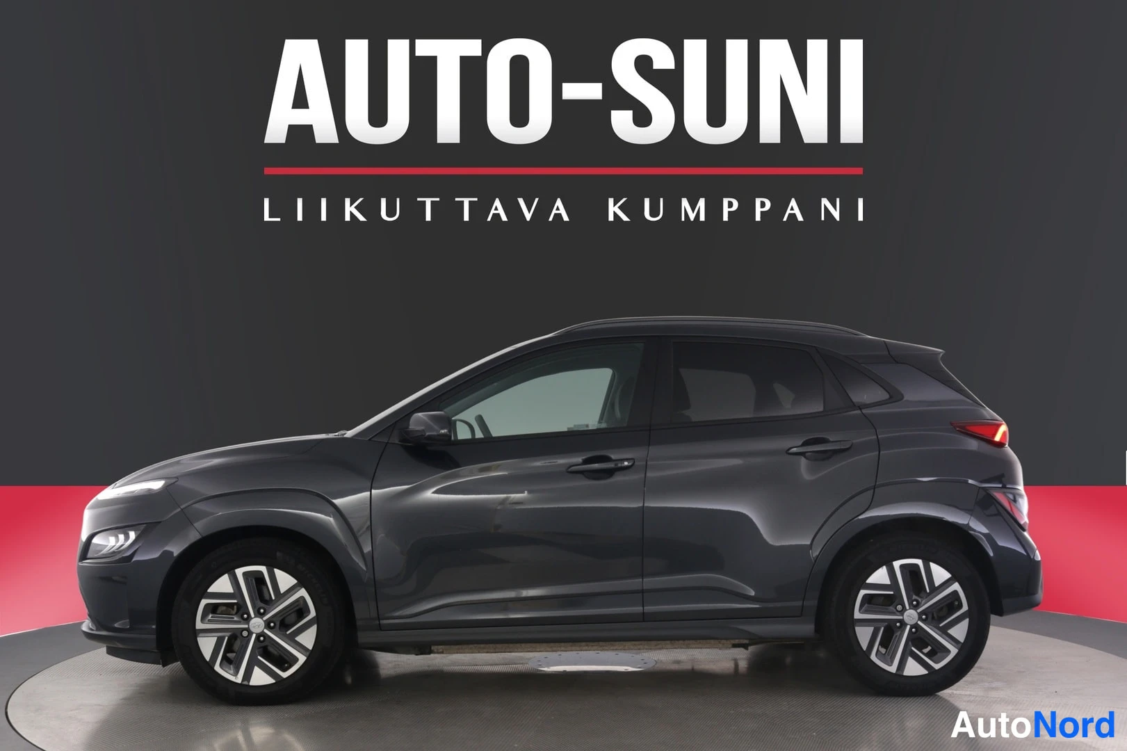 Etuviisto, nokka vasemmalle: Hyundai Kona -mallin kylki ja keula tummanharmaana kuvattuna studiotakinalta vasemmalta edestä.