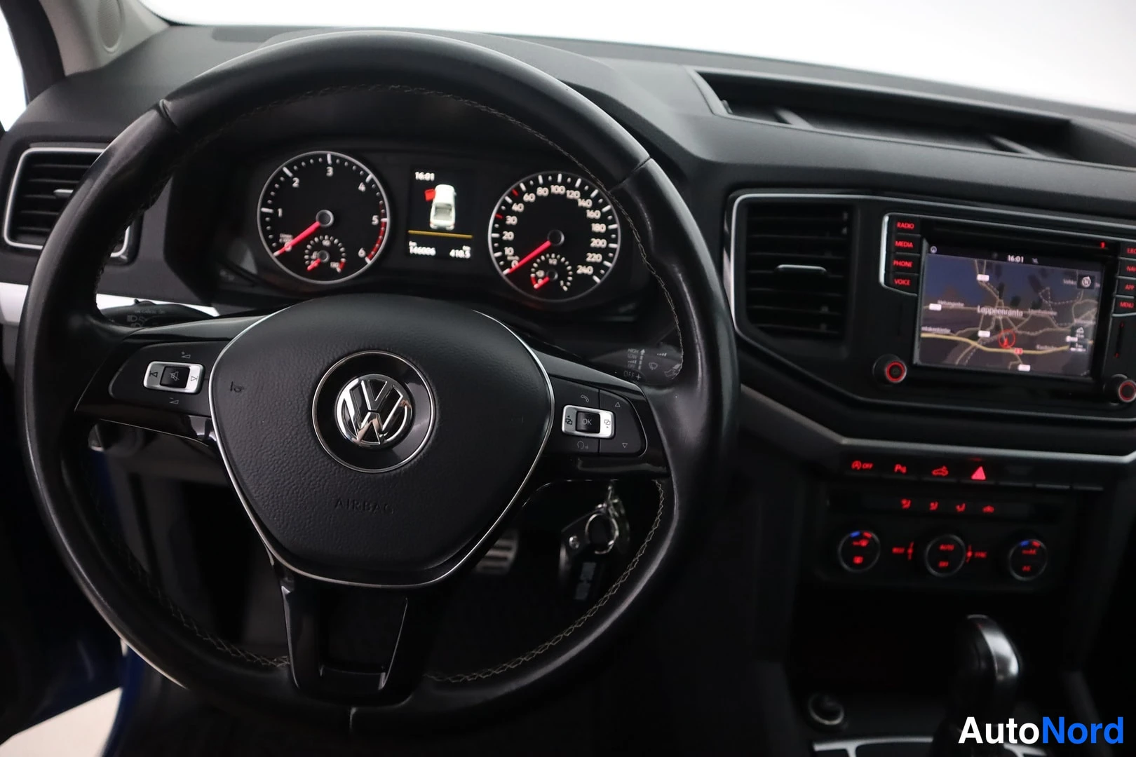 Muu: Sisäkuva ohjaamosta: Volkswagen-merkkiohjauspyörä, analoginen mittaristo, kartan näyttävä infotainment-näyttö sekä manuaalivaihteiston vaihdekeila.