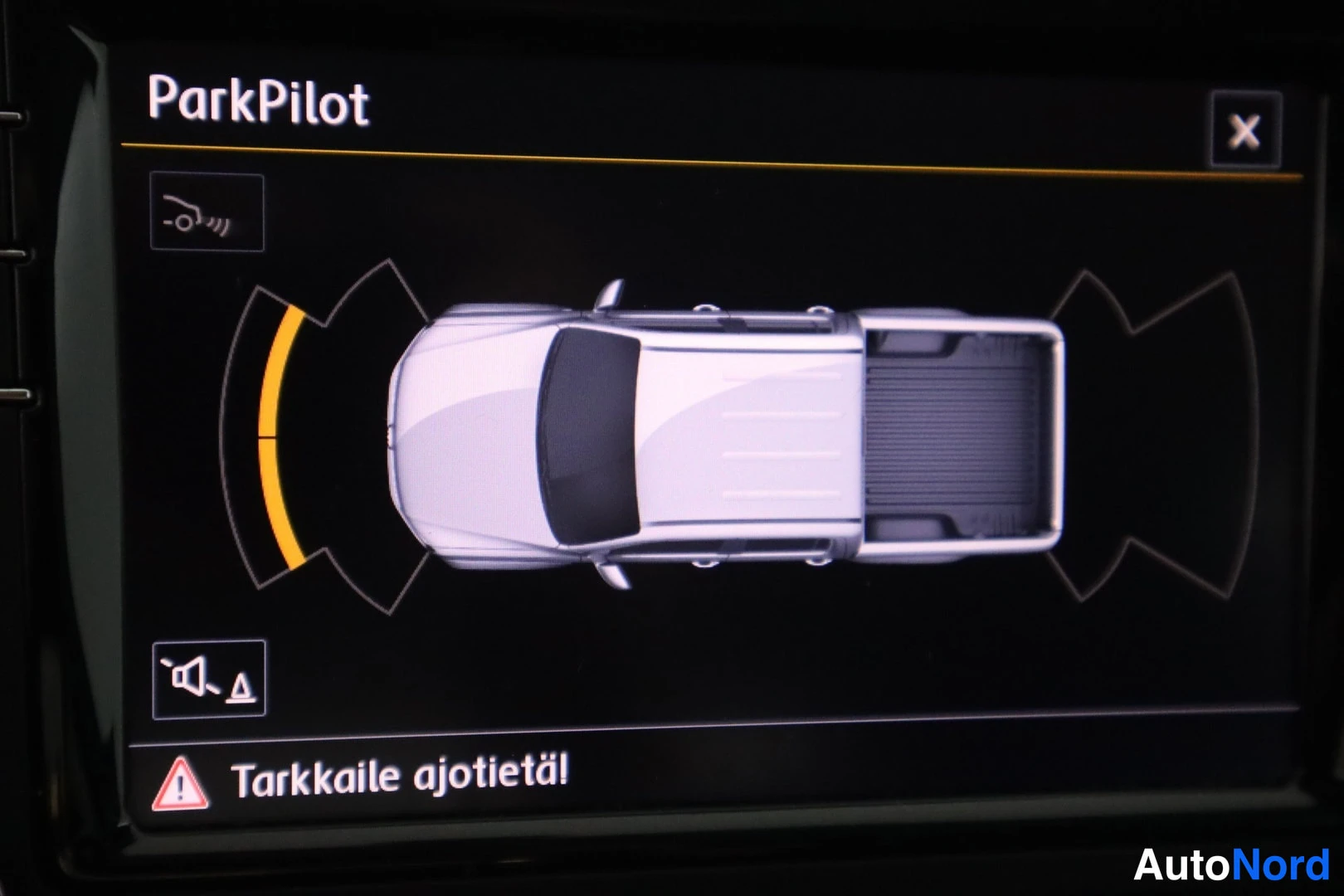 Yksityiskohta: A close-up of the infotainment screen displaying the ParkPilot parking system. The screen shows a top-down graphic representation of a white pickup truck with a