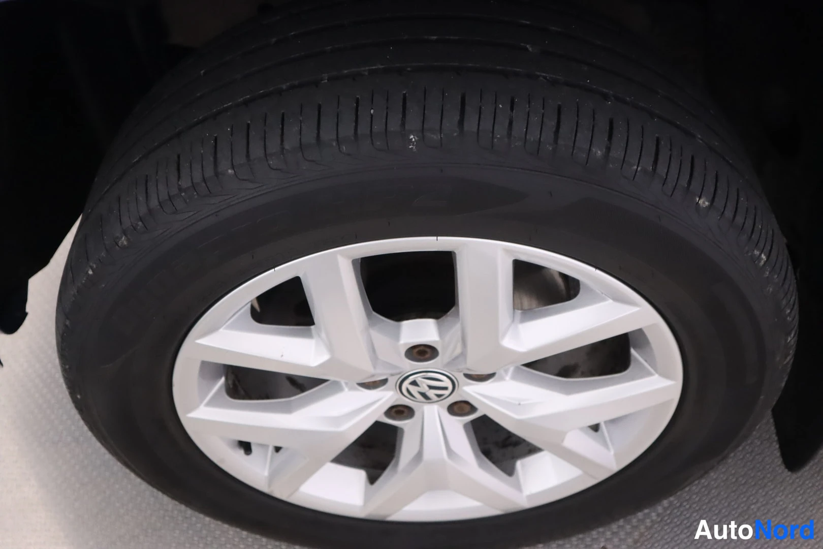 Sivulta: Lähikuva auton pyörästä hopeisella monihaaravanteella, jossa Volkswagenin merkki; musta rengas.