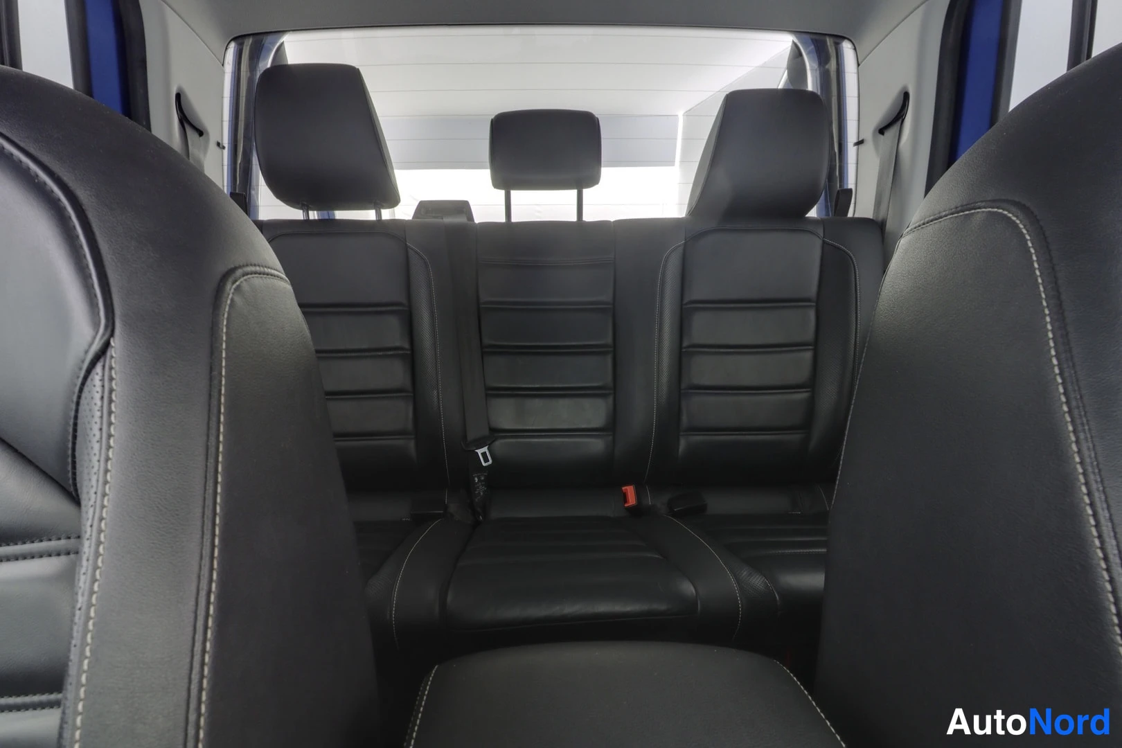 Takaistuimet: Rear passenger compartment showing black leather bench seat with three headrests and ISOFIX child seat anchor points.