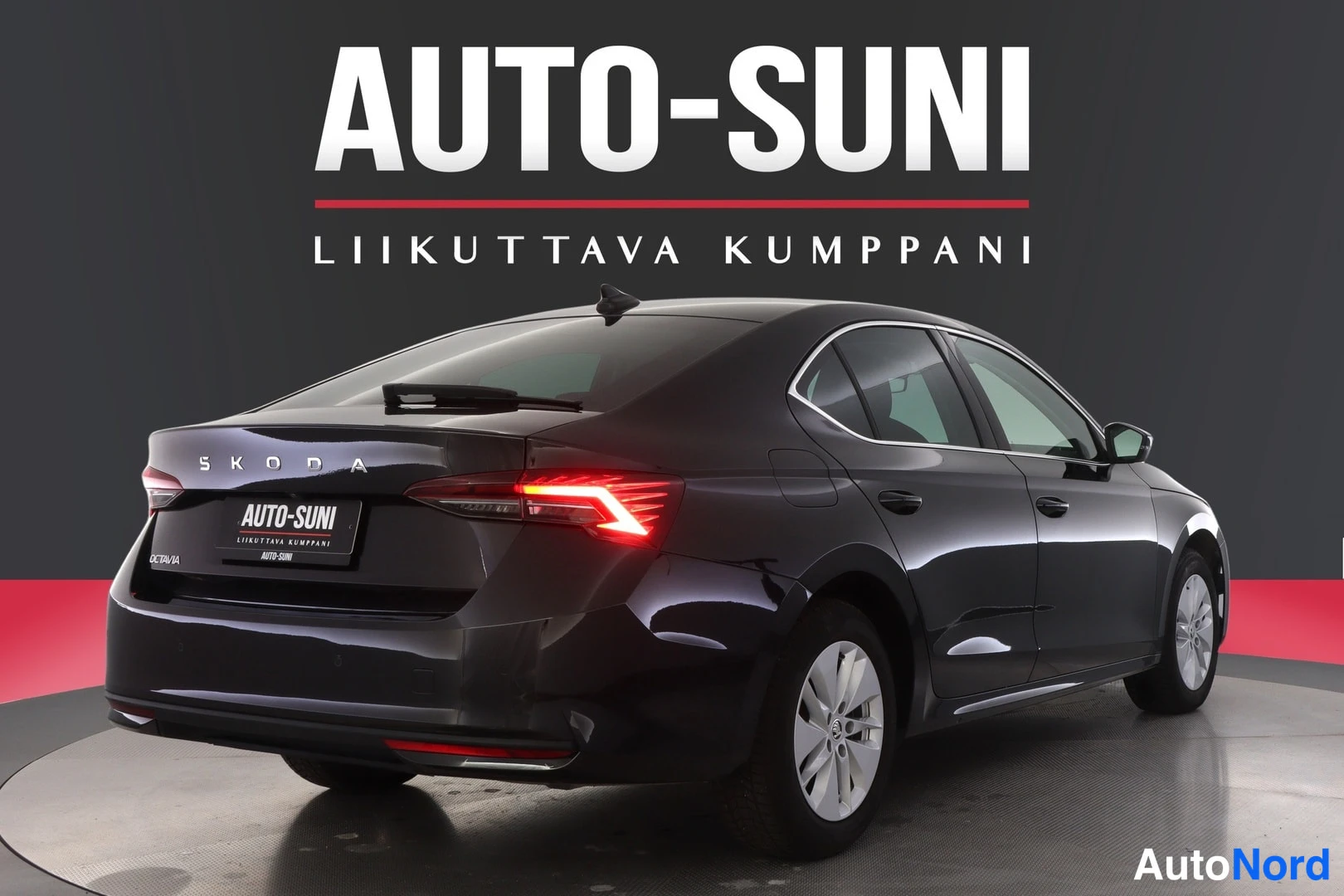 Takaviisto: Tumman mustan sedanin takakulma studiotäyttökuvassa: takavalo, tavaratilan kansi ŠKODA-tekstillä, takapuskurin ilmaanotto ja auton oikea kylki ovineen ja renkai