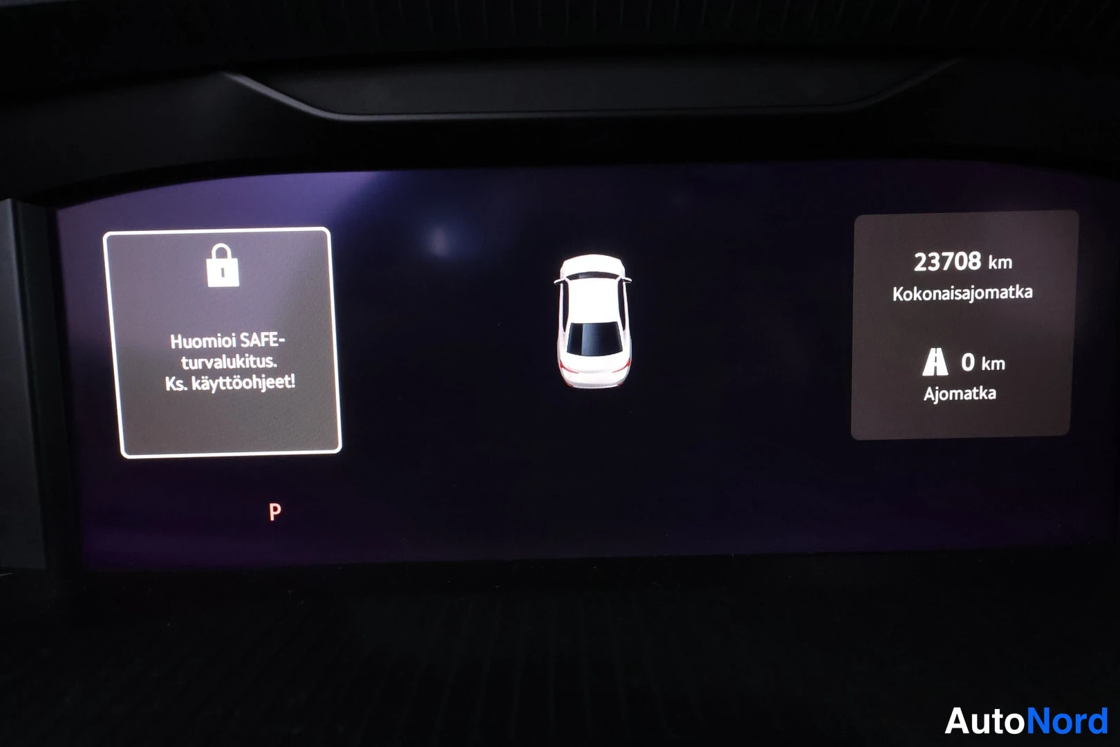 Etuviisto: Kojelaudan näyttö ilmoittaa tekstillä 'Huomioi SAFE-turvalukitus. Ks. käyttöohjeet!'; näytöllä myös auton kuva, kokonaisajomatka 23708 km, ajomatka 0 km ja vaih