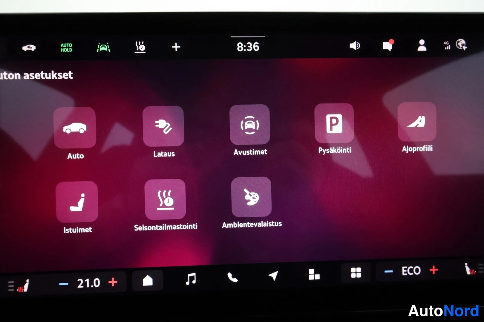 Muu: Auton infotainment-näyttö, jossa on auki asetusvalikko kuvakkeineen: Auto, Lataus, Avustimet, Pysäköinti, Ajoprofiili, Istuimet, Seisontailmastointi ja Ambiente