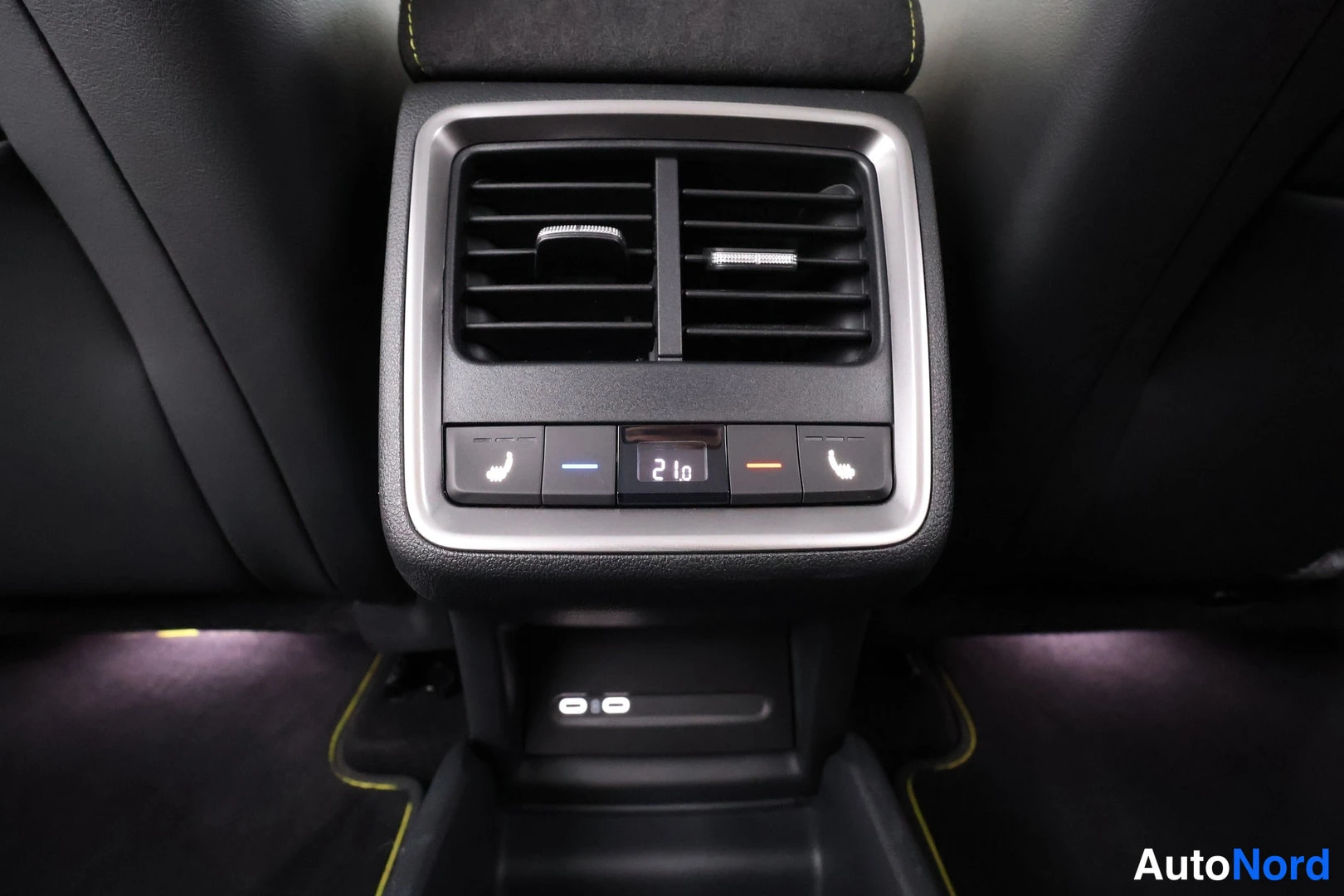 Tavaratila: Rear center console air vents and climate controls located between the front seats. The digital display reads '21.0'. Controls include heated seat icons (chair