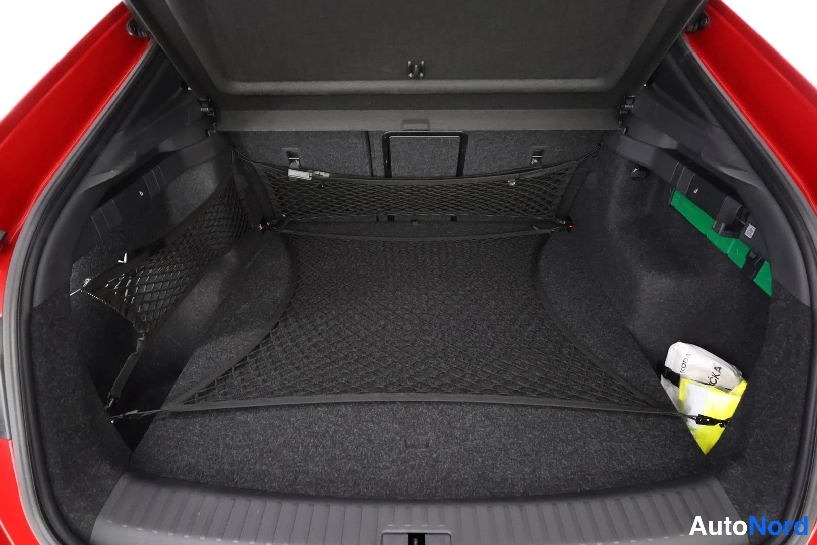 Tavaratila: Avoin tavaratila. Kaksi mustaa verkkoverkkoa kiinnitettyinä sivuseiniin. Oikealla puolelta osittain näkyvä keltainen ja valkoinen esine, jossa lukee ''4x4''.