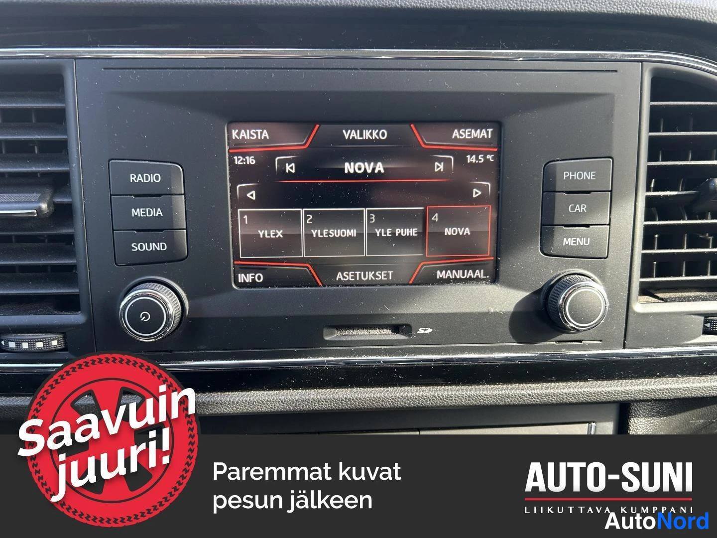 Yksityiskohta: Keskikonsolin näyttö ja painikkeet: radiolista asemilla YLEX, YLESUOMI, YLE PUHE ja NOVA; painikkeet RADIO, MEDIA, SOUND, PHONE, CAR ja MENU.